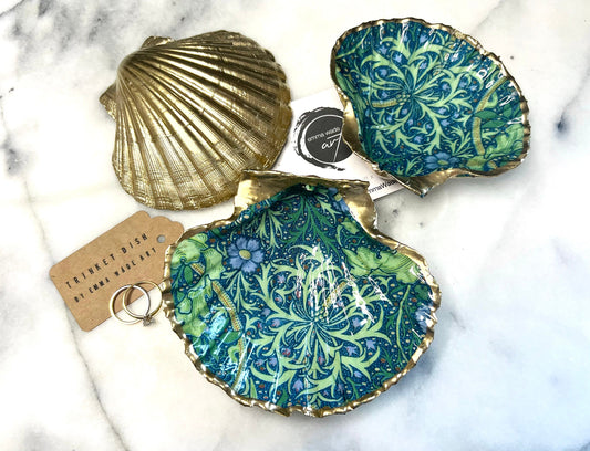 Handmade William Morris inspired scallop shell trinket dish in green and blue tones, featuring a seaweed decoupage design. Finished with gold leaf and sealed with glossy resin. Coastal jewellery dish made from a UK scallop shell, perfect for holding rings, earrings and small treasures. Decorative shell bowl photographed on a light background, showing the natural shell shape and gilded edges.