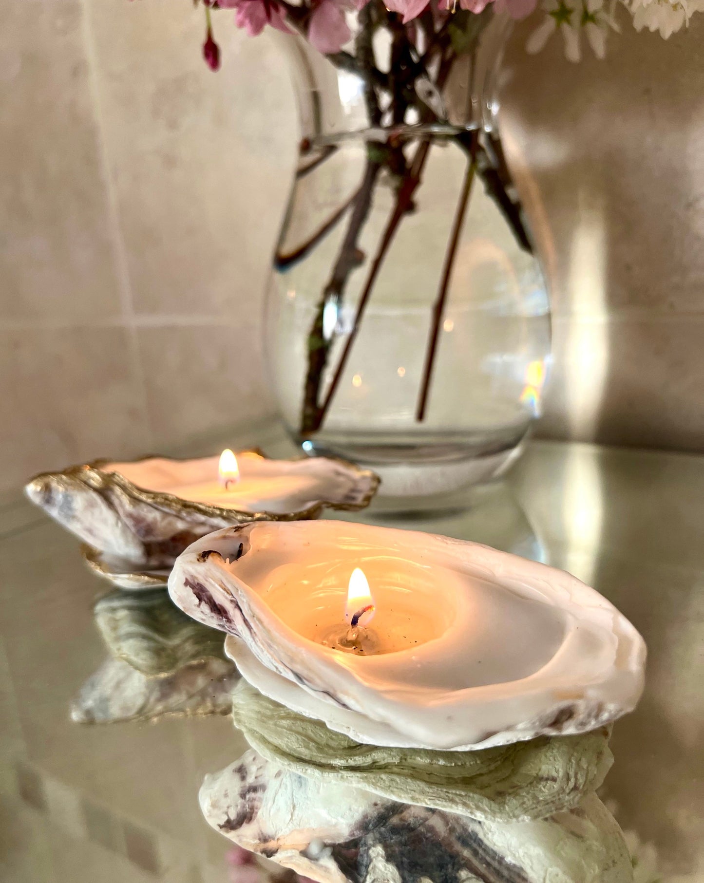 Luxury oyster shell candle hand poured with natural vegetable wax inside a real Dorset oyster shell with gold leaf edging. Coastal candle decor with polished pearl shell interior and artisan handmade styling. Sustainable shell candle gift for weddings, birthdays, spa decor and coastal home interiors.