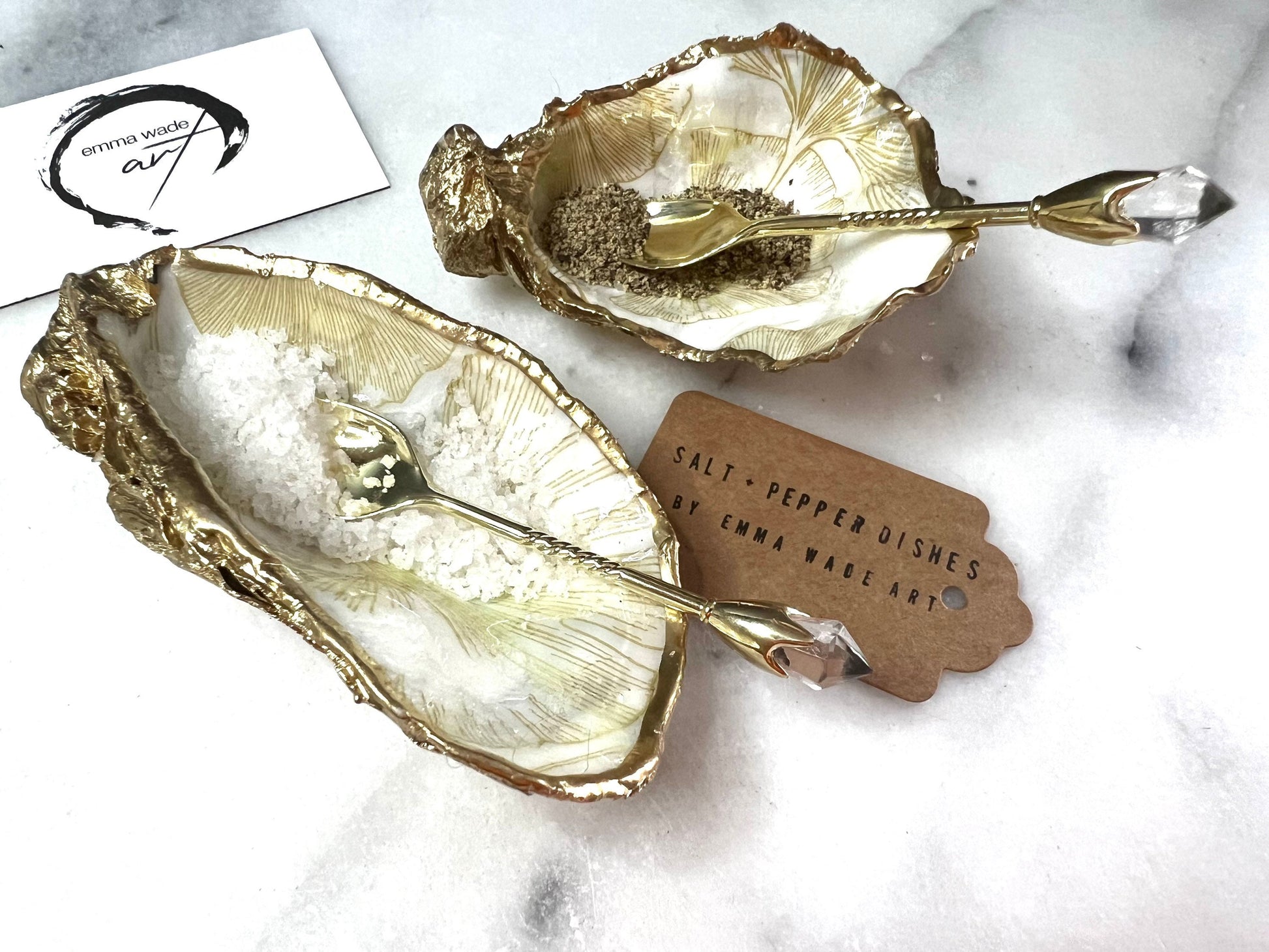 Pair of handmade Dorset oyster shell salt and pepper pinch pots featuring elegant Japanese Ginkgo floral artwork in soft gold and pearl tones with hand-applied gold leaf edging. Coastal luxury cruet set sealed in glossy Crystal resin with optional gold crystal spoons.