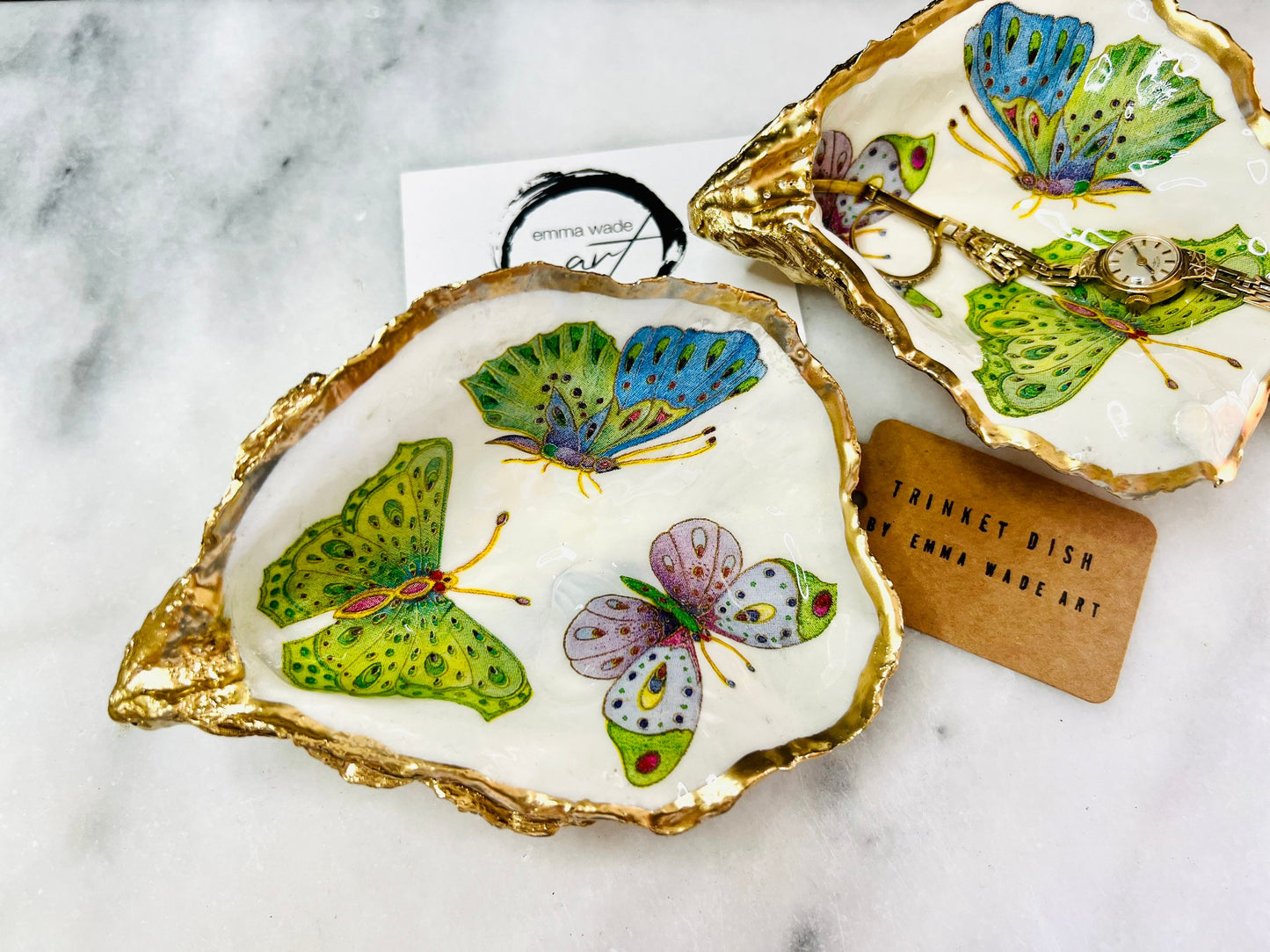 Handmade butterfly oyster shell trinket dish with colourful blue green and pink butterfly designs, edged and backed in gold leaf, Dorset coastal shell jewellery holder with glossy resin finish, luxury ring dish, coastal home decor gift, unique handmade shell dish for jewellery storage, beach house accessory, UK artisan oyster shell dish
