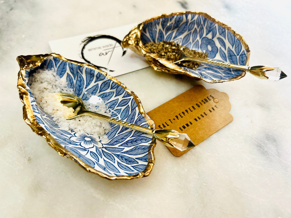 Sustainable Dorset oyster shell cruet set featuring blue floral designs and real gold leaf edges | Handmade salt and pepper pinch pots, sealed with food-safe glossy resin and presented in a sustainable kraft gift box | A unique salt gift for weddings, anniversaries, and coastal dining | Includes optional gold crystal spoons | Perfect handmade gift for beach house decor or ocean-inspired table styling | Maimekko Design