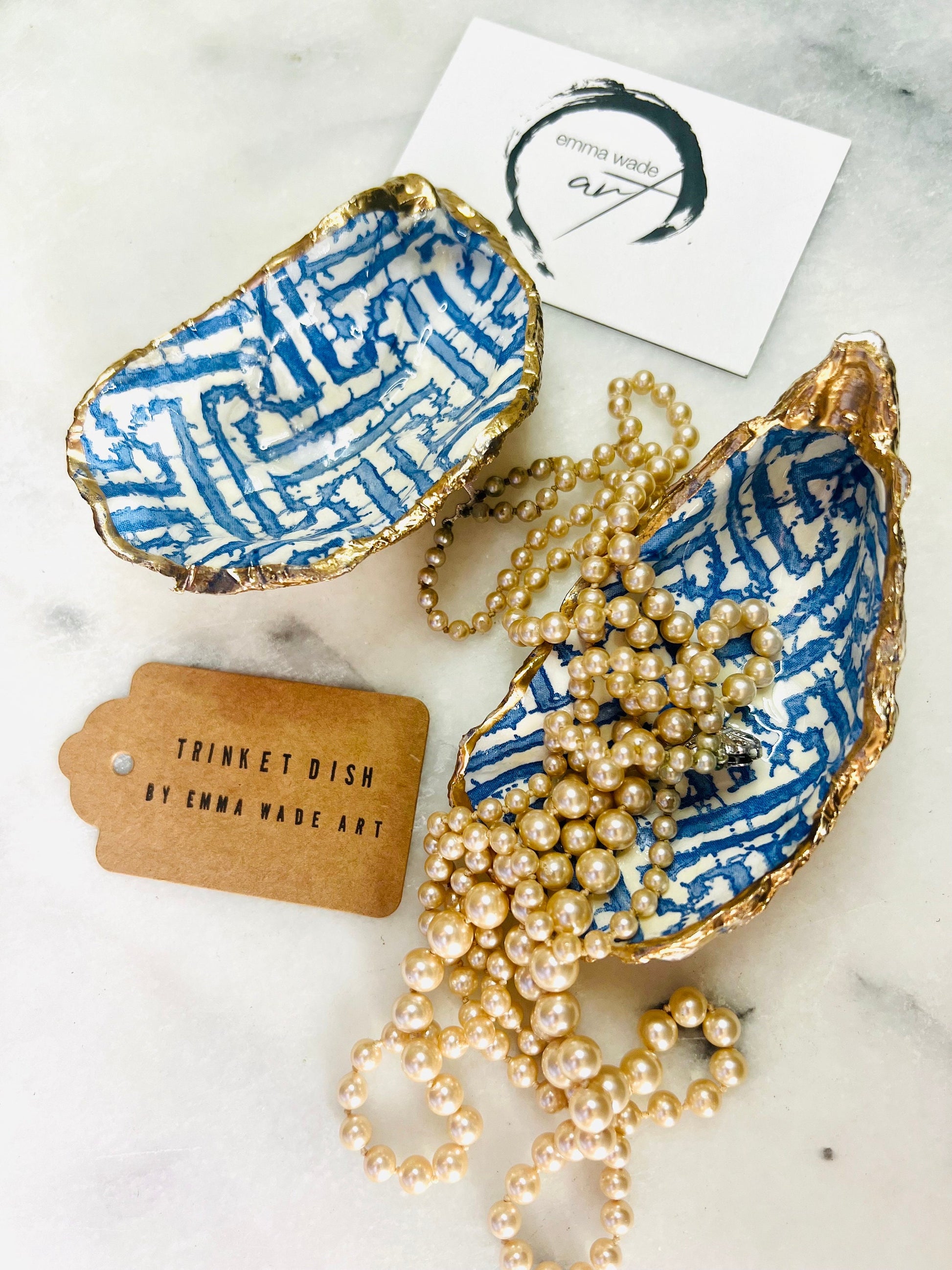 Handmade blue fretwork oyster shell trinket dish shown as a single piece, crafted from a natural Dorset oyster shell and finished with genuine gold leaf edges and glossy resin. Featuring an intricate blue fretwork pattern, this jewellery and ring holder is perfect for a bedside table, bathroom or coastal-inspired decor. Each shell is one of a kind and carefully finished by hand.