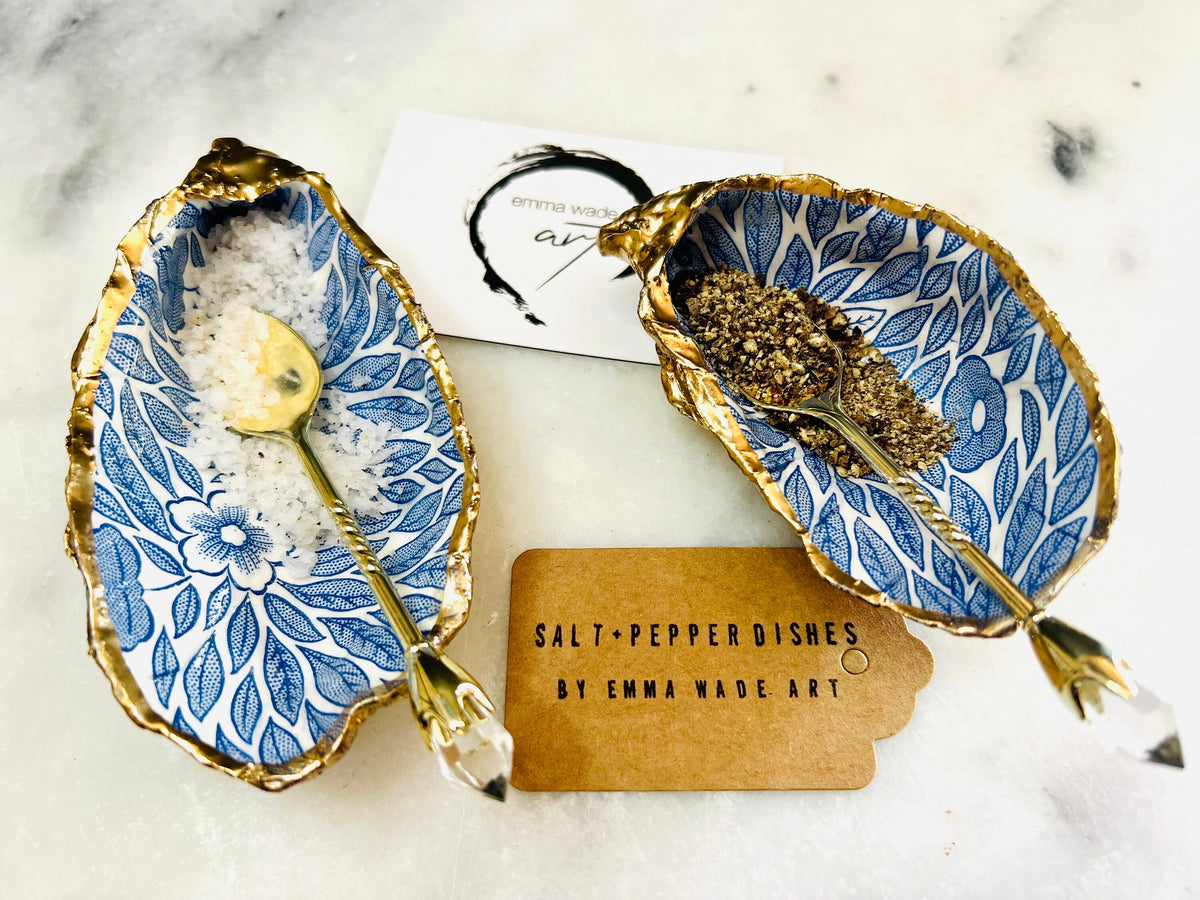 Sustainable Dorset oyster shell cruet set featuring blue floral designs and real gold leaf edges | Handmade salt and pepper pinch pots, sealed with food-safe glossy resin and presented in a sustainable kraft gift box | A unique salt gift for weddings, anniversaries, and coastal dining | Includes optional gold crystal spoons | Perfect handmade gift for beach house decor or ocean-inspired table styling | Maimekko Design