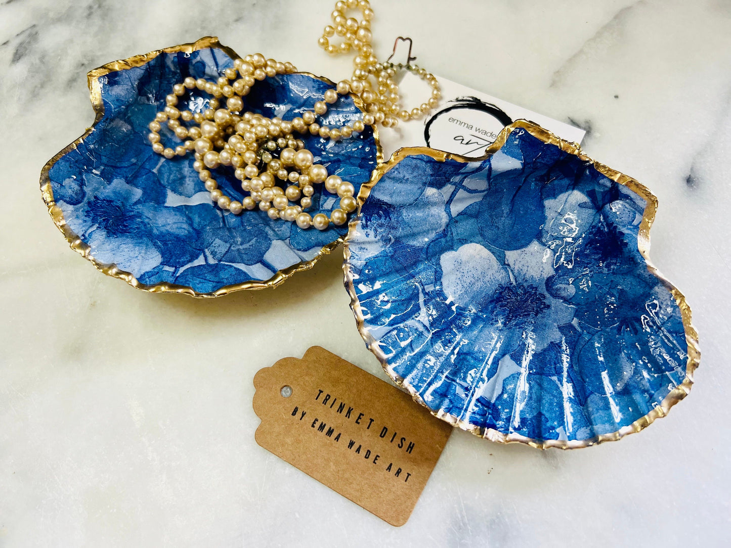 Deep blue watercolour floral scallop shell trinket dish with hand gilded gold leaf edging and glossy resin finish. Handmade Dorset shell jewellery holder in rich cobalt and ocean blue tones, styled as coastal home décor with pearls and gold details.