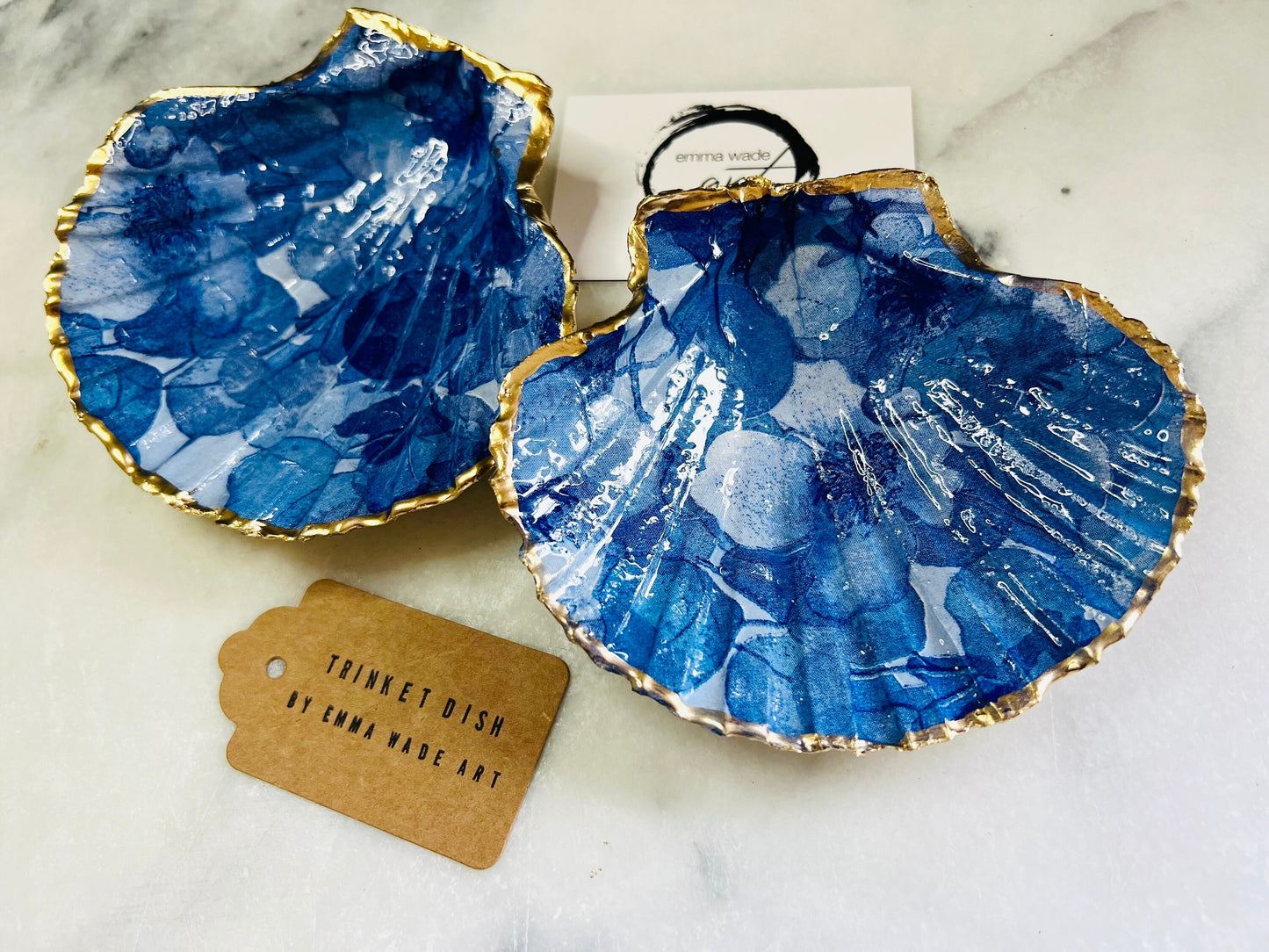 Deep blue watercolour floral scallop shell trinket dish with hand gilded gold leaf edging and glossy resin finish. Handmade Dorset shell jewellery holder in rich cobalt and ocean blue tones, styled as coastal home décor with pearls and gold details.