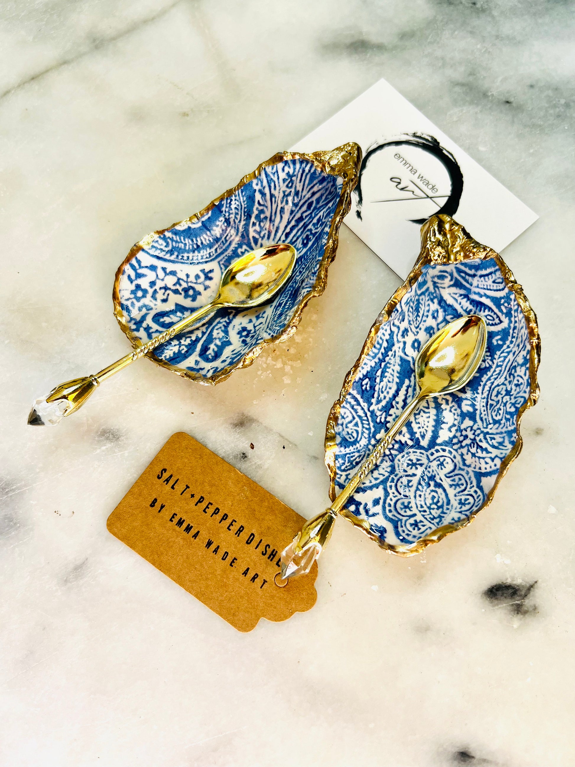 Blue and white paisley oyster shell salt cellar set with gold leaf edging and matching gold crystal spoons. Handmade Dorset oyster shell pinch pots finished in glossy food safe resin. Coastal dining decor and luxury beach house table accessory.