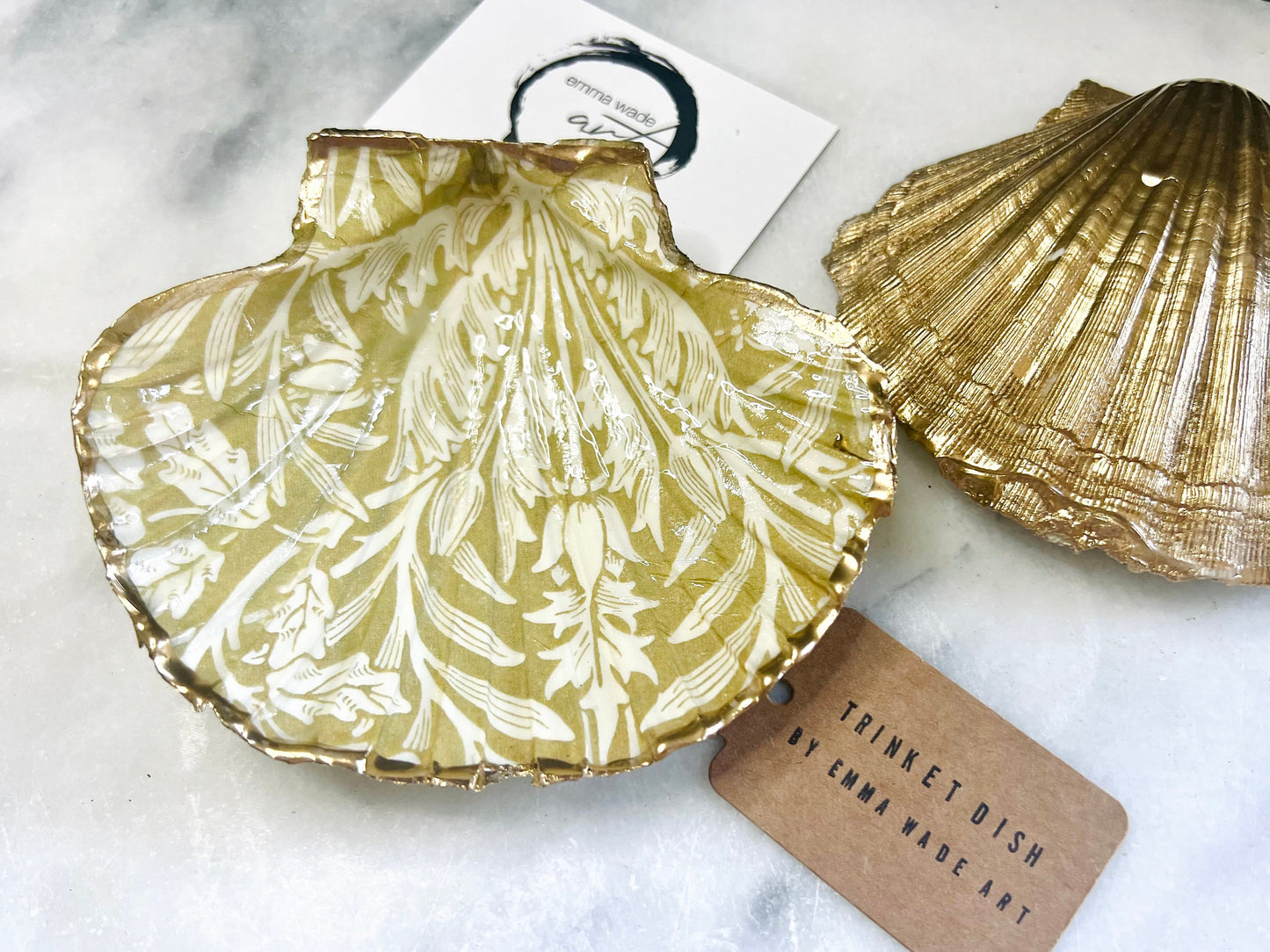 Handmade scallop shell trinket dishes featuring a William Morris gold and ivory acorn heritage pattern with shimmering liquid gold leaf edging. Natural Dorset scallop shells sealed in glossy crystal clear resin and styled as luxury jewellery holders, vanity trays and coastal home décor accessories. Elegant Arts and Crafts inspired shell dishes photographed on a marble background with pearls and decorative styling.