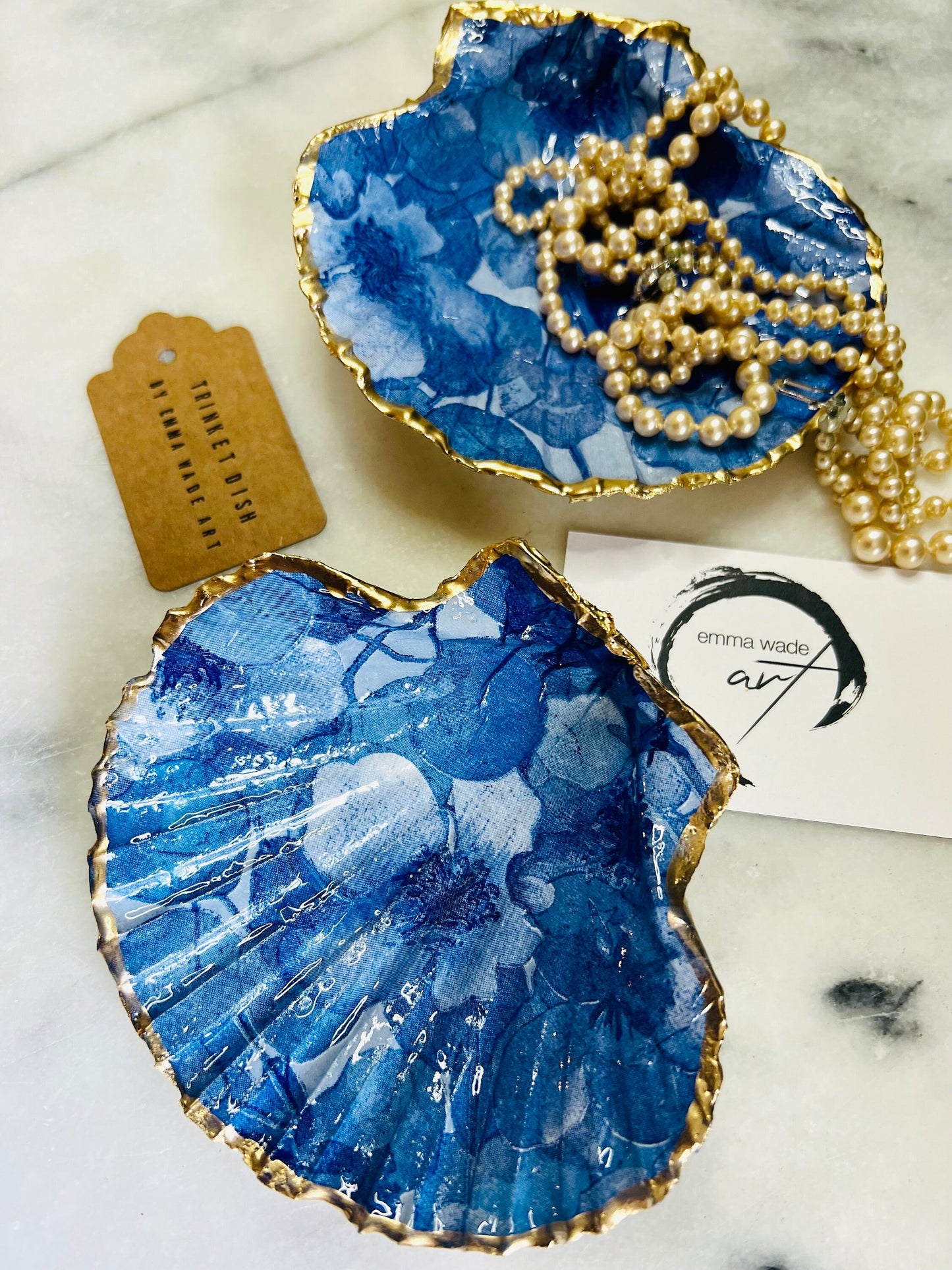 Deep blue watercolour floral scallop shell trinket dish with hand gilded gold leaf edging and glossy resin finish. Handmade Dorset shell jewellery holder in rich cobalt and ocean blue tones, styled as coastal home décor with pearls and gold details.