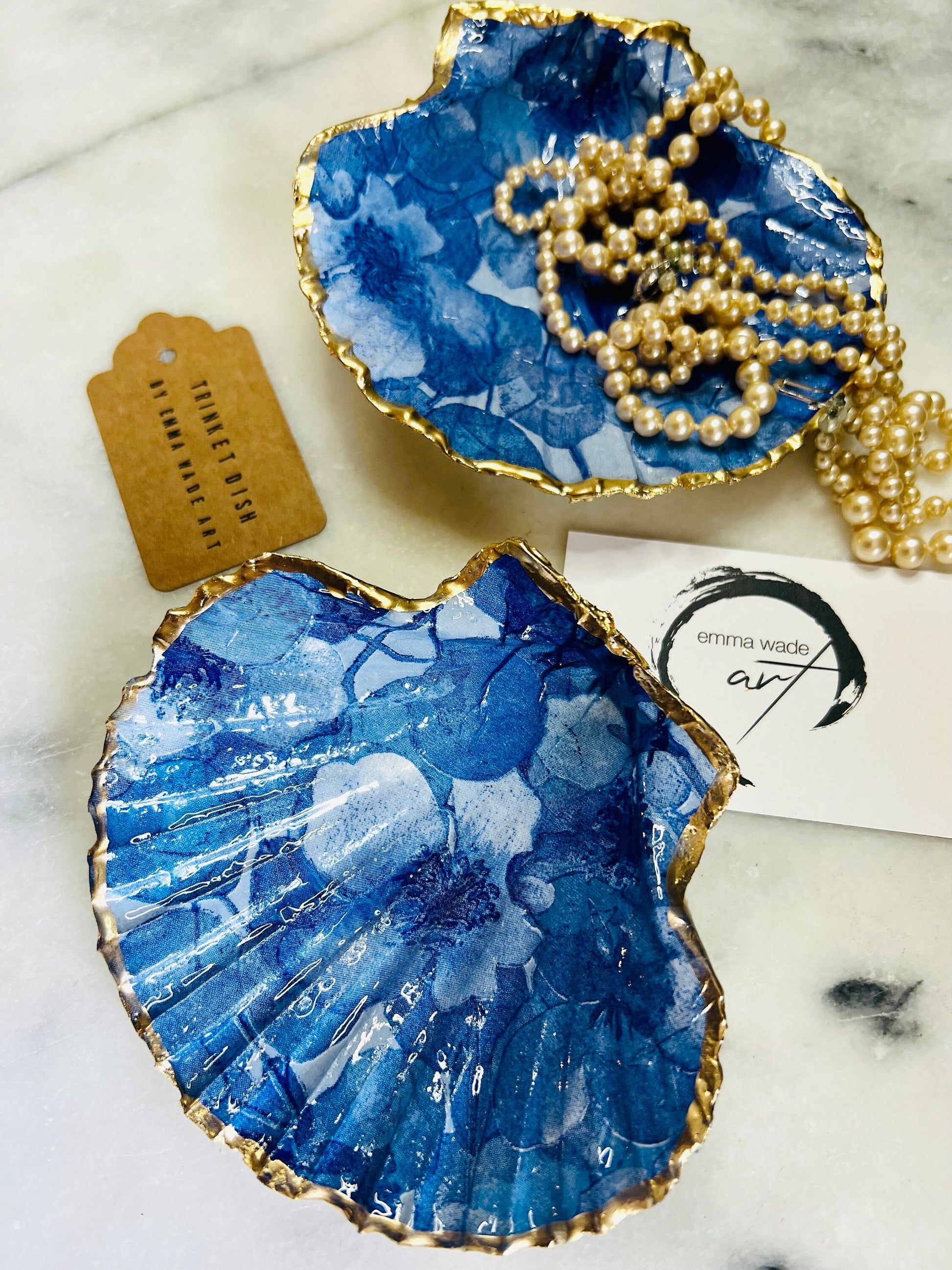 Deep blue watercolour floral scallop shell trinket dish with hand gilded gold leaf edging and glossy resin finish. Handmade Dorset shell jewellery holder in rich cobalt and ocean blue tones, styled as coastal home décor with pearls and gold details.