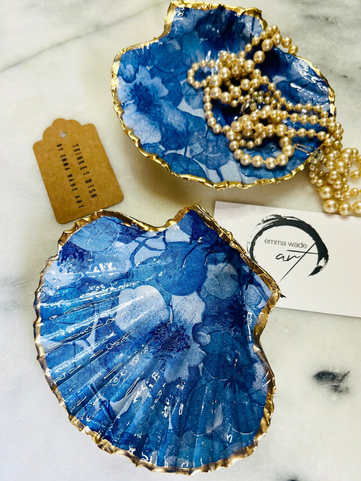 Deep blue watercolour floral scallop shell trinket dish with hand gilded gold leaf edging and glossy resin finish. Handmade Dorset shell jewellery holder in rich cobalt and ocean blue tones, styled as coastal home décor with pearls and gold details.