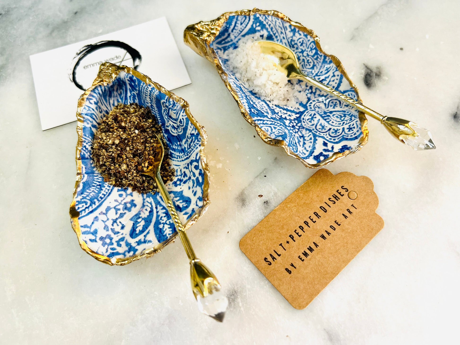 Blue and white paisley oyster shell salt cellar set with gold leaf edging and matching gold crystal spoons. Handmade Dorset oyster shell pinch pots finished in glossy food safe resin. Coastal dining decor and luxury beach house table accessory.