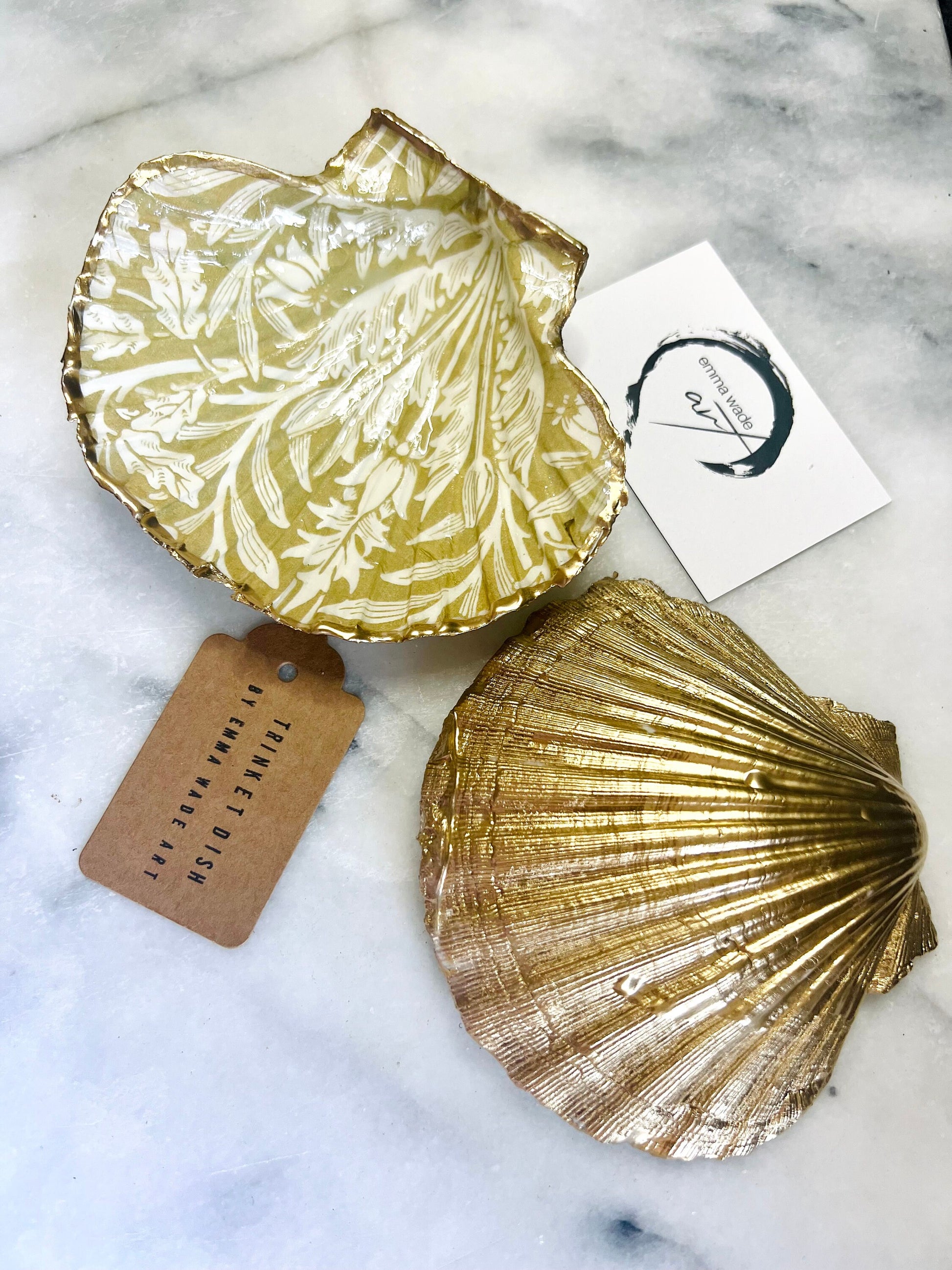 Handmade scallop shell trinket dishes featuring a William Morris gold and ivory acorn heritage pattern with shimmering liquid gold leaf edging. Natural Dorset scallop shells sealed in glossy crystal clear resin and styled as luxury jewellery holders, vanity trays and coastal home décor accessories. Elegant Arts and Crafts inspired shell dishes photographed on a marble background with pearls and decorative styling.