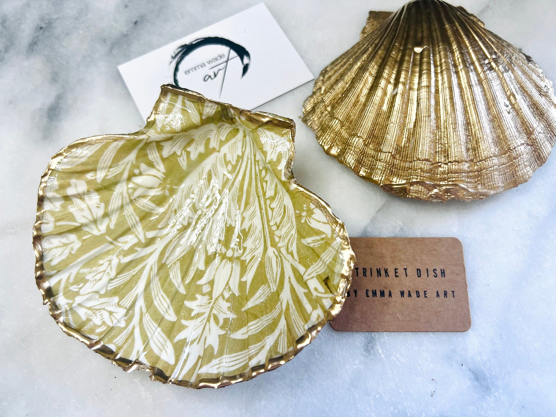 Handmade scallop shell trinket dishes featuring a William Morris gold and ivory acorn heritage pattern with shimmering liquid gold leaf edging. Natural Dorset scallop shells sealed in glossy crystal clear resin and styled as luxury jewellery holders, vanity trays and coastal home décor accessories. Elegant Arts and Crafts inspired shell dishes photographed on a marble background with pearls and decorative styling.