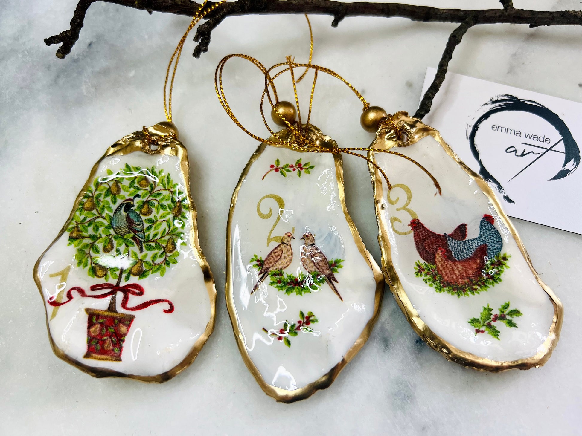 Handmade Twelve Days of Christmas oyster shell ornament set featuring all twelve traditional carol illustrations, finished with gold leaf edging, glossy resin and gold hanging cords. Coastal heirloom Christmas decorations handcrafted from Dorset oyster shells.
