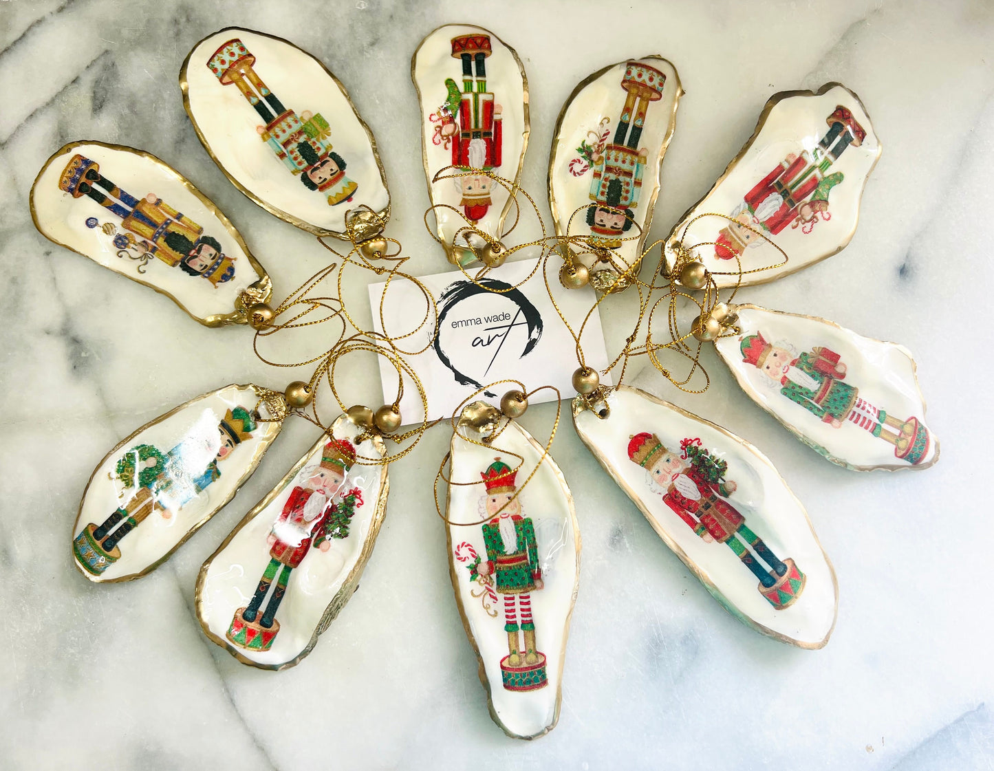 Handmade Nutcracker oyster shell Christmas ornaments with gold gilded edges and glossy resin finish. Traditional festive Nutcracker designs on natural pearl Dorset oyster shells in red, green, aqua, blue and gold tones, styled as luxury coastal Christmas tree decorations.
