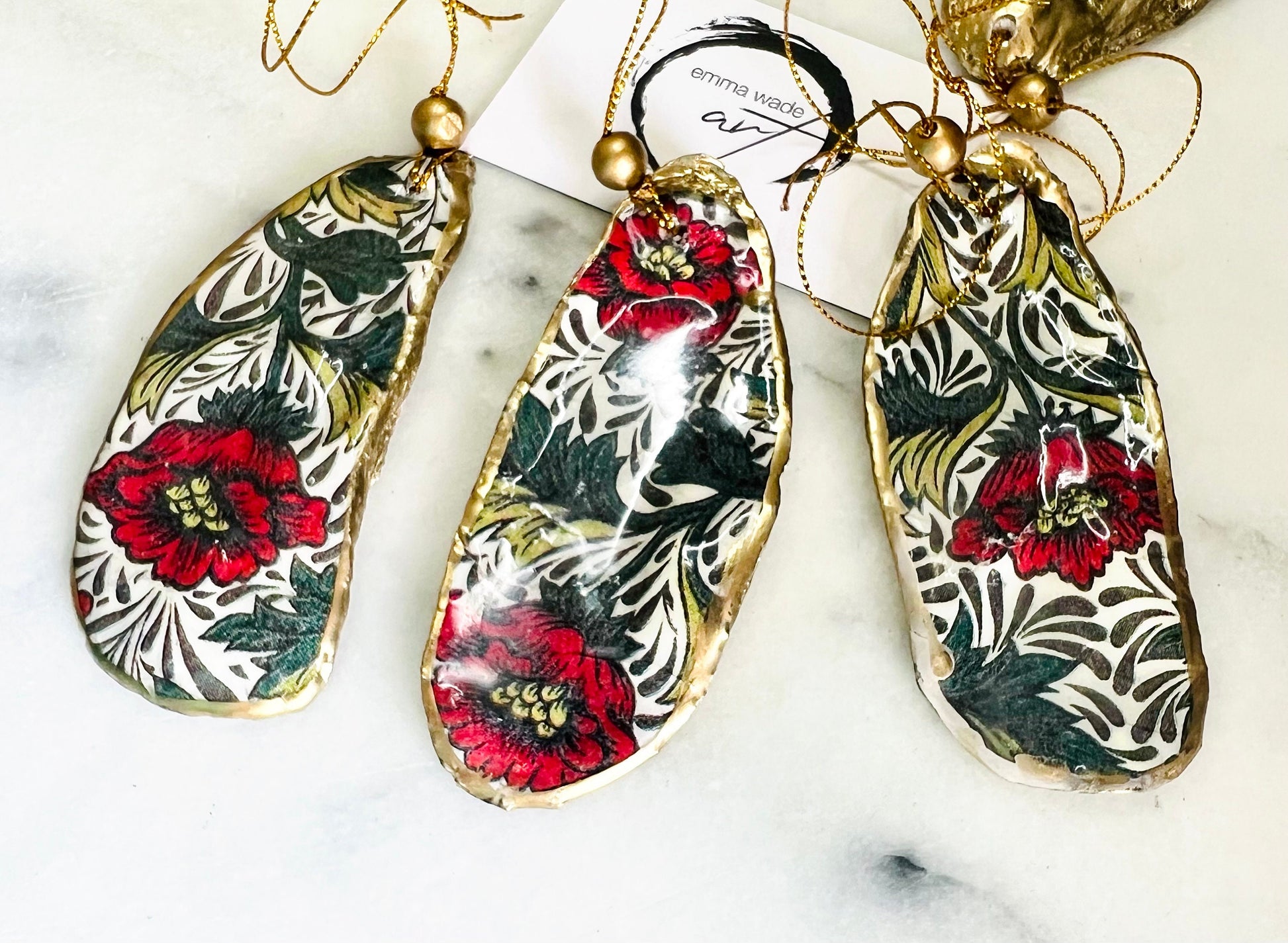 Handmade Dorset oyster shell hanging ornaments featuring William Morris inspired Red Peony botanical floral design in rich red, cream and deep green tones. Natural oyster shells with polished pearlescent interiors, hand edged with liquid gold leaf and sealed with glossy resin for shine and durability. Elegant botanical coastal décor suitable as Christmas ornaments, floral hanging décor, cottagecore home accessories or thoughtful artisan gifts. Available individually or as curated sets.