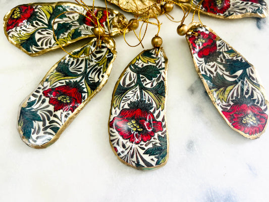 Handmade Dorset oyster shell hanging ornaments featuring William Morris inspired Red Peony botanical floral design in rich red, cream and deep green tones. Natural oyster shells with polished pearlescent interiors, hand edged with liquid gold leaf and sealed with glossy resin for shine and durability. Elegant botanical coastal décor suitable as Christmas ornaments, floral hanging décor, cottagecore home accessories or thoughtful artisan gifts. Available individually or as curated sets.