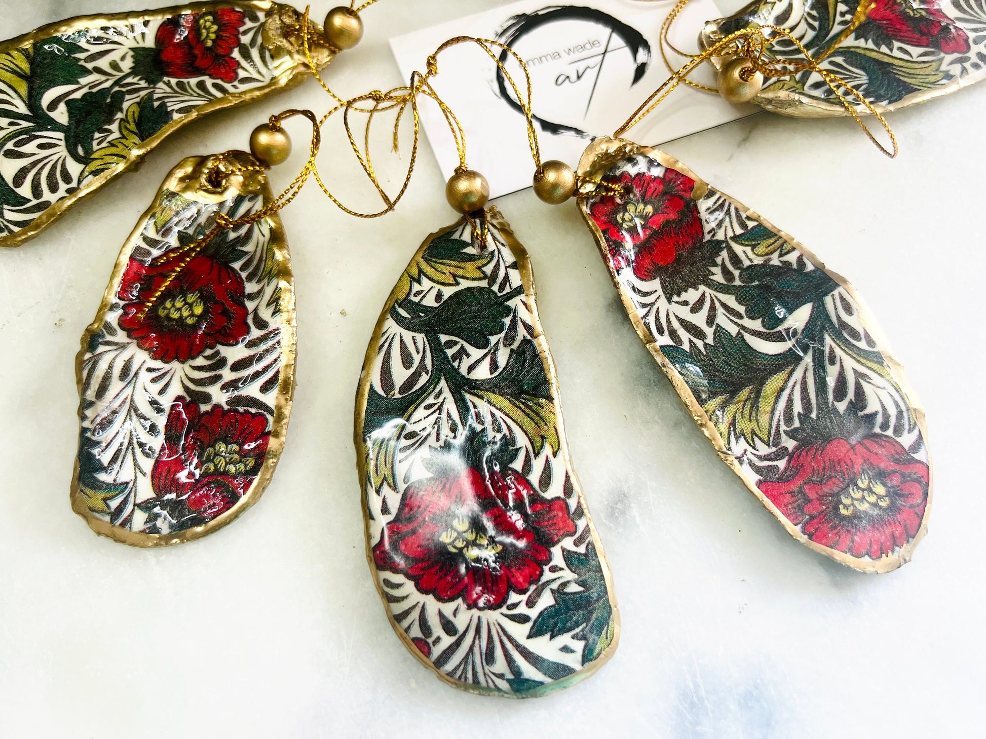Handmade Dorset oyster shell hanging ornaments featuring William Morris inspired Red Peony botanical floral design in rich red, cream and deep green tones. Natural oyster shells with polished pearlescent interiors, hand edged with liquid gold leaf and sealed with glossy resin for shine and durability. Elegant botanical coastal décor suitable as Christmas ornaments, floral hanging décor, cottagecore home accessories or thoughtful artisan gifts. Available individually or as curated sets.