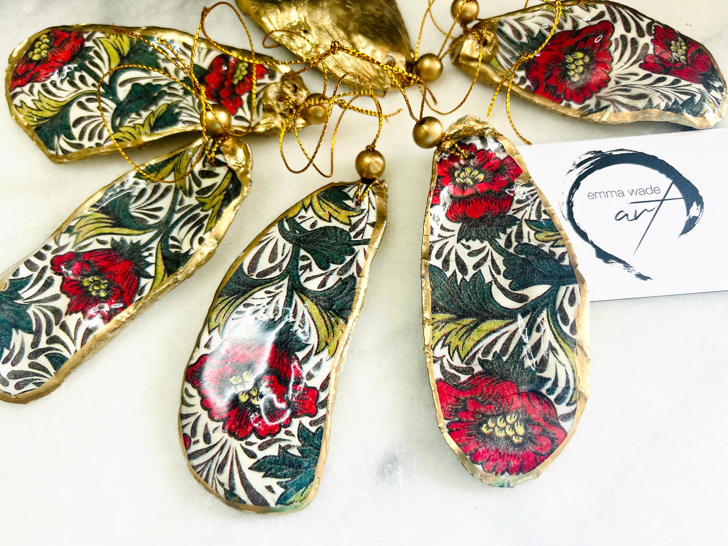 Handmade Dorset oyster shell hanging ornaments featuring William Morris inspired Red Peony botanical floral design in rich red, cream and deep green tones. Natural oyster shells with polished pearlescent interiors, hand edged with liquid gold leaf and sealed with glossy resin for shine and durability. Elegant botanical coastal décor suitable as Christmas ornaments, floral hanging décor, cottagecore home accessories or thoughtful artisan gifts. Available individually or as curated sets.