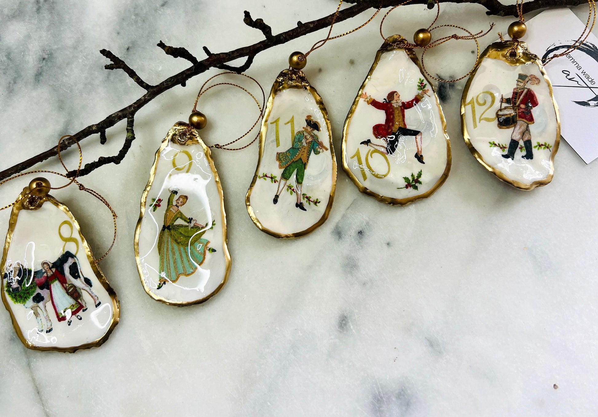 Handmade Twelve Days of Christmas oyster shell ornament set featuring all twelve traditional carol illustrations, finished with gold leaf edging, glossy resin and gold hanging cords. Coastal heirloom Christmas decorations handcrafted from Dorset oyster shells.