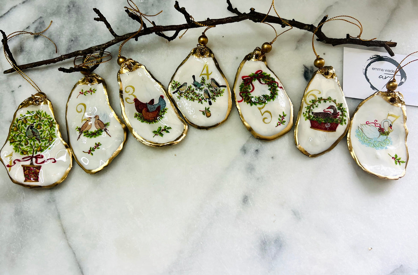 Handmade Twelve Days of Christmas oyster shell ornament set featuring all twelve traditional carol illustrations, finished with gold leaf edging, glossy resin and gold hanging cords. Coastal heirloom Christmas decorations handcrafted from Dorset oyster shells.
