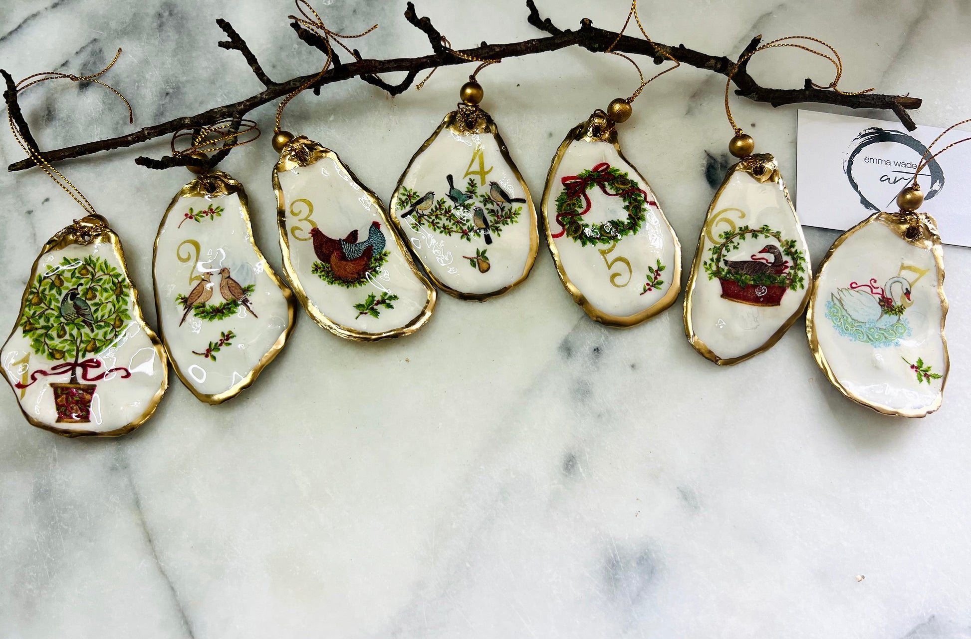 Handmade Twelve Days of Christmas oyster shell ornament set featuring all twelve traditional carol illustrations, finished with gold leaf edging, glossy resin and gold hanging cords. Coastal heirloom Christmas decorations handcrafted from Dorset oyster shells.
