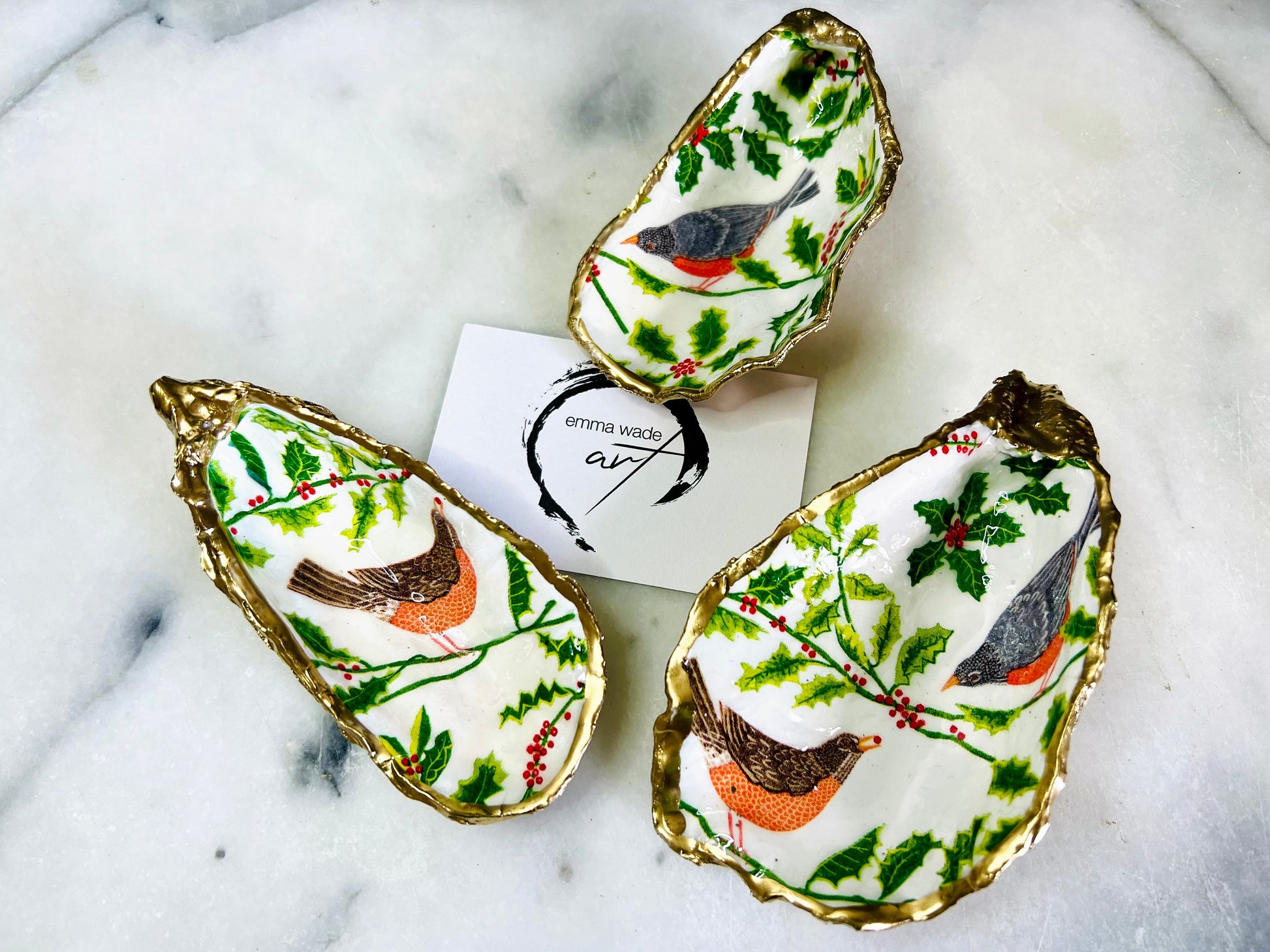 Handmade Dorset oyster shell dish decorated with winter birds in red and orange, finished with gold leaf edging and glossy resin. Each shell is unique and can be used as a trinket dish, ring holder, or converted into a hanging ornament with drilled hole and twine. Options available: standard red bird, standard orange bird, or large red and orange bird design. Perfect as a Christmas tree ornament, stocking filler, festive decoration, or handmade gift for weddings, anniversaries, or birthdays.