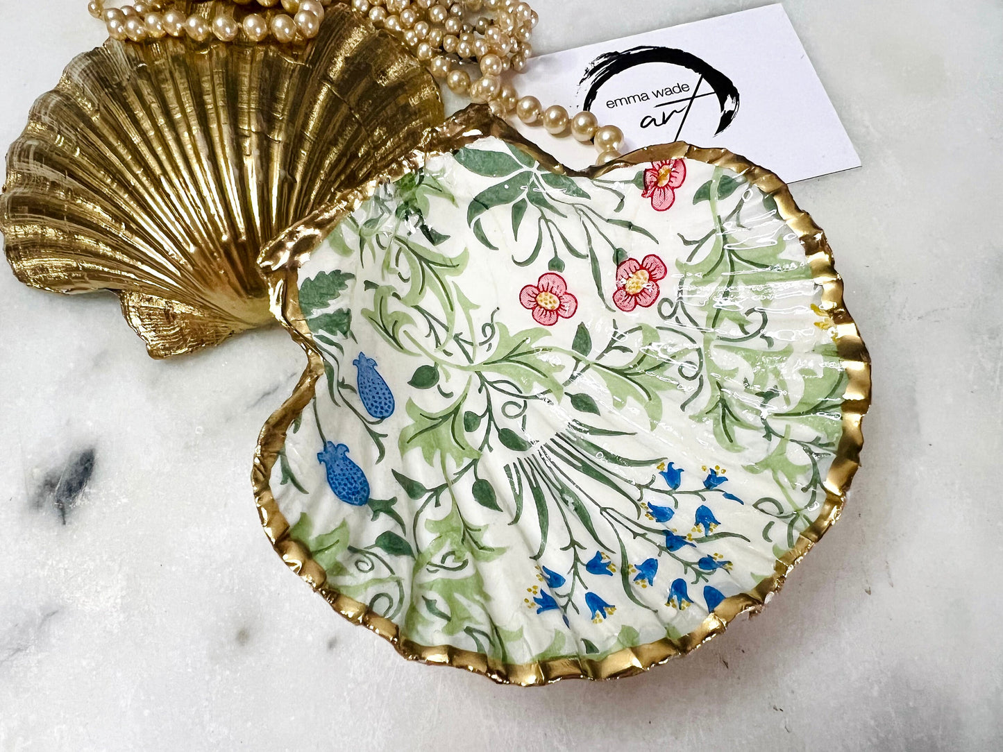 Handmade Dorset scallop shell dish featuring William Morris Celandine floral design in green, red, and blue. Each shell is finished with liquid gold leaf on the rim and back, sealed with crystal-clear resin for a glossy, durable finish. A unique scallop shell jewellery dish, ring holder, or trinket tray for earrings, cufflinks, and keepsakes. Perfect as a handmade William Morris gift, coastal-inspired ornament, or decorative tray for weddings, anniversaries, birthdays and Christmas