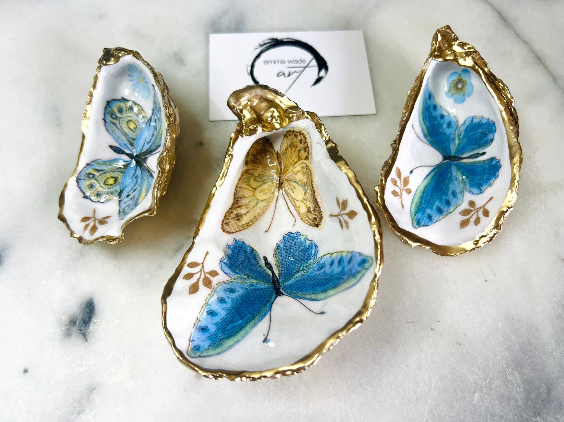 Blue yellow green butterfly oyster shell trinket dish handmade from Dorset coast shell, gold leaf gilded rim and back, high gloss resin interior with colourful butterfly design, coastal home decor jewellery dish, ring holder, trinket tray, seaside gift for her, handmade shell decor, luxury coastal accessory, unique artisan gift UK