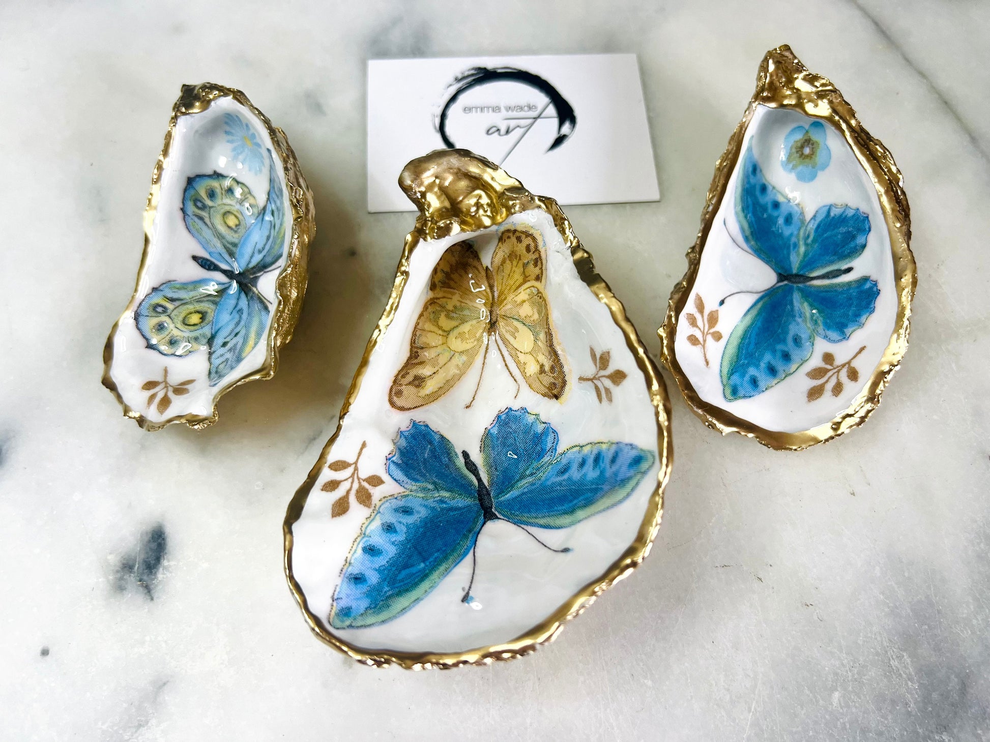 Blue yellow green butterfly oyster shell trinket dish handmade from Dorset coast shell, gold leaf gilded rim and back, high gloss resin interior with colourful butterfly design, coastal home decor jewellery dish, ring holder, trinket tray, seaside gift for her, handmade shell decor, luxury coastal accessory, unique artisan gift UK