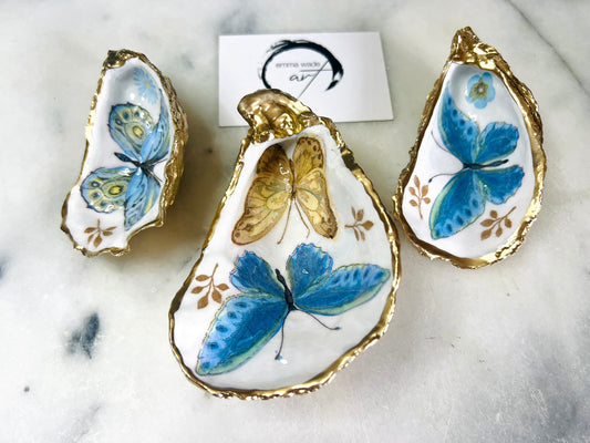 Blue yellow green butterfly oyster shell trinket dish handmade from Dorset coast shell, gold leaf gilded rim and back, high gloss resin interior with colourful butterfly design, coastal home decor jewellery dish, ring holder, trinket tray, seaside gift for her, handmade shell decor, luxury coastal accessory, unique artisan gift UK