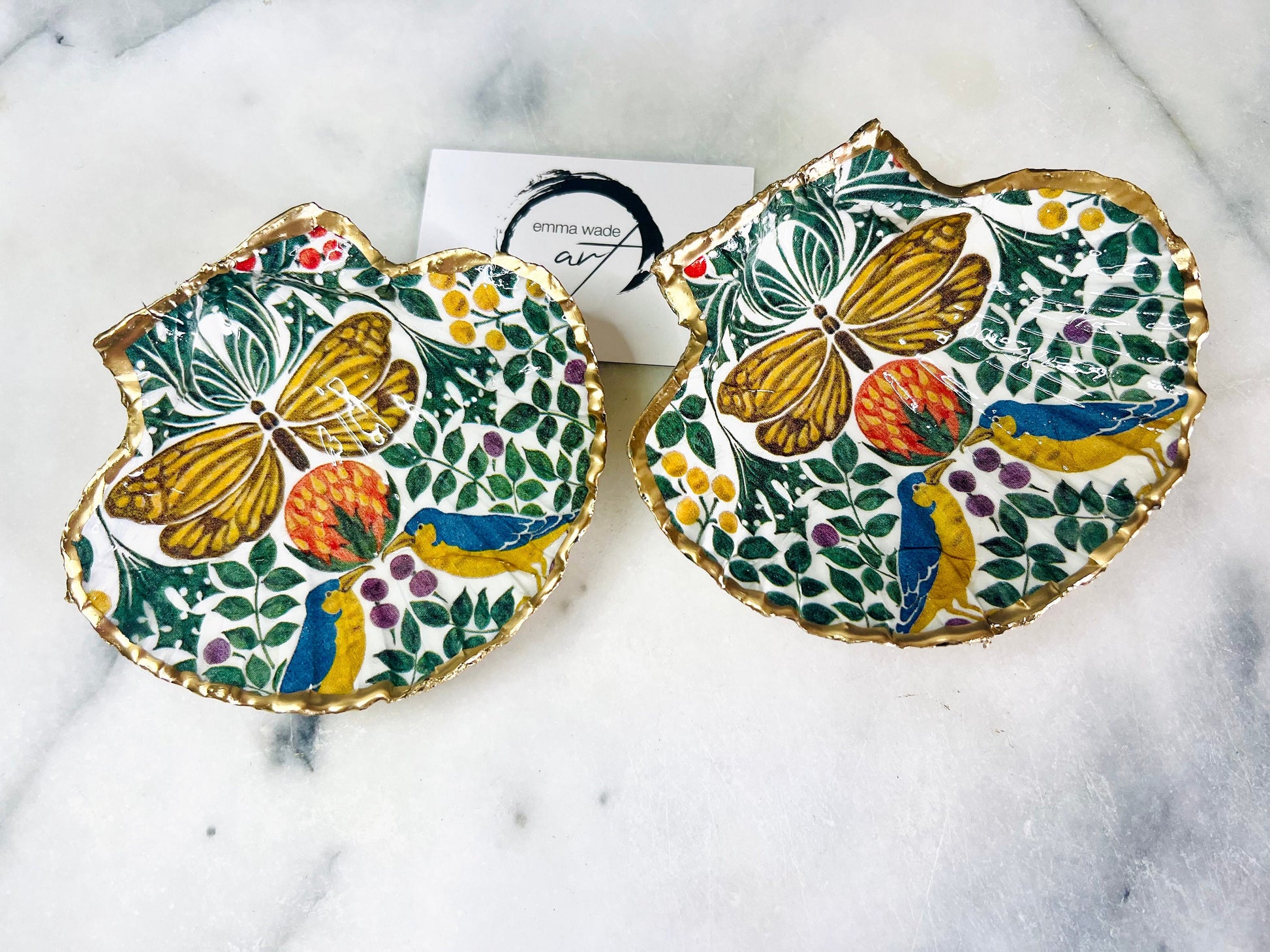 Handmade scallop shell trinket dishes with bird and butterfly design, finished with gold leaf and glossy resin, shown as decorative jewellery trays on a light background, coastal inspired handmade Dorset shell decor.