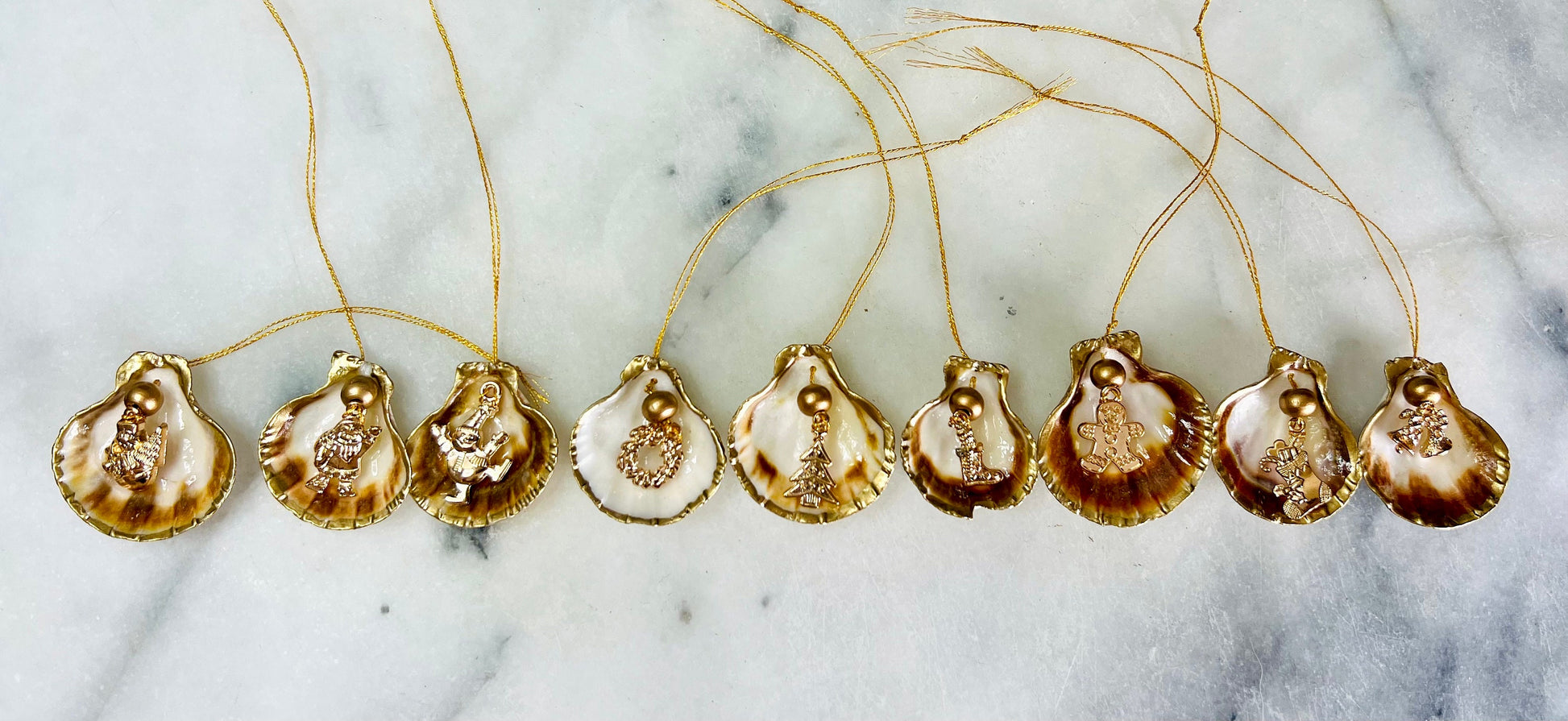 Handmade scallop shell Christmas ornaments with gold leaf edging and enamel charms, natural pearl shell decorations, Dorset shell baubles, festive tree decorations, stocking filler gifts, coastal Christmas decor, small hanging ornaments with gold string, unique handmade shell keepsake, wreath sleigh tree reindeer bell penguin charms, luxury Christmas gift idea