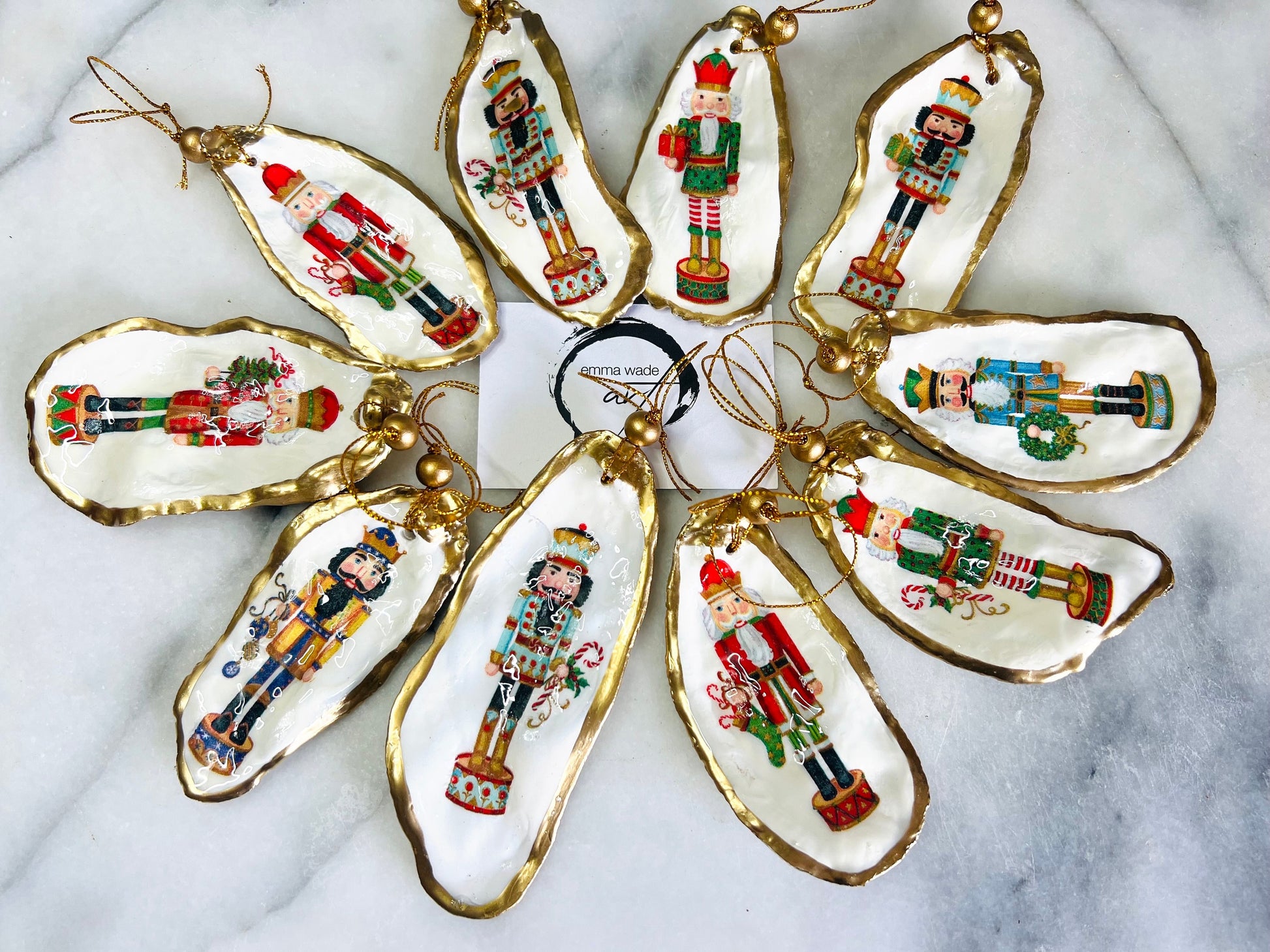 Handmade Nutcracker oyster shell Christmas ornaments with gold gilded edges and glossy resin finish. Traditional festive Nutcracker designs on natural pearl Dorset oyster shells in red, green, aqua, blue and gold tones, styled as luxury coastal Christmas tree decorations.