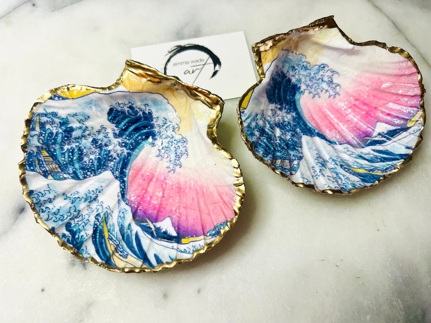Handcrafted Great Wave of Kanagawa scallop shell trinket dish inspired by Hokusai’s iconic Japanese woodblock print. Each Dorset shell is hand-drawn, painted, and sealed in resin, with a choice of Dawn or Dusk design. Finished with a natural varnished back and gold rim or fully gilded in liquid gold leaf. A unique handmade jewellery holder or coastal art gift, beautifully presented in sustainable packaging.