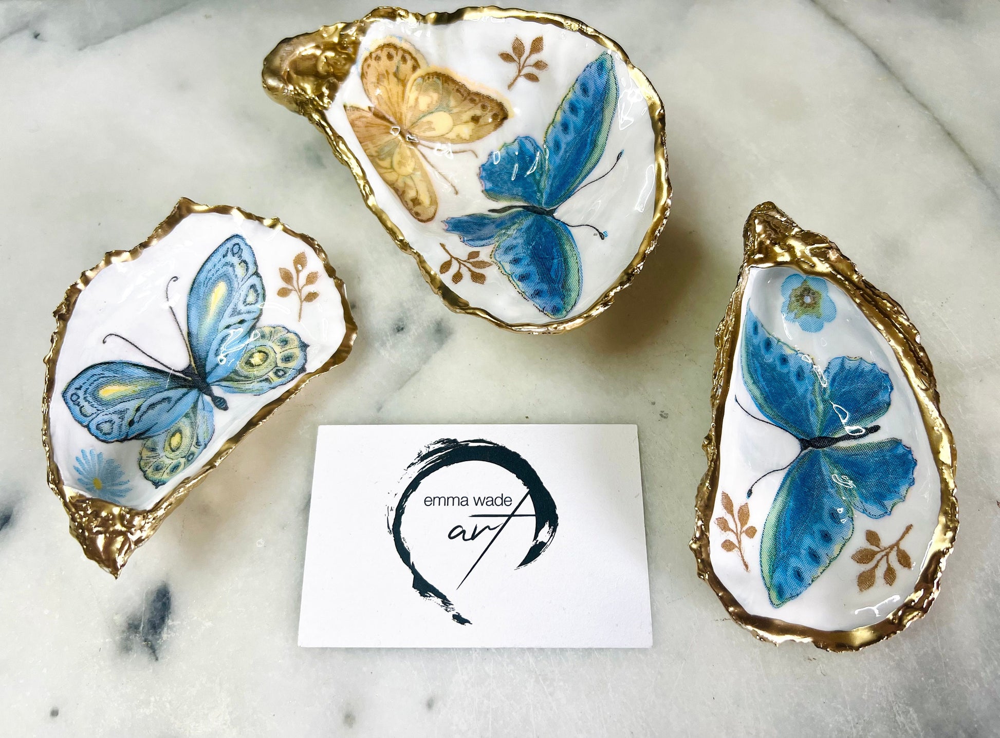 Blue yellow green butterfly oyster shell trinket dish handmade from Dorset coast shell, gold leaf gilded rim and back, high gloss resin interior with colourful butterfly design, coastal home decor jewellery dish, ring holder, trinket tray, seaside gift for her, handmade shell decor, luxury coastal accessory, unique artisan gift UK