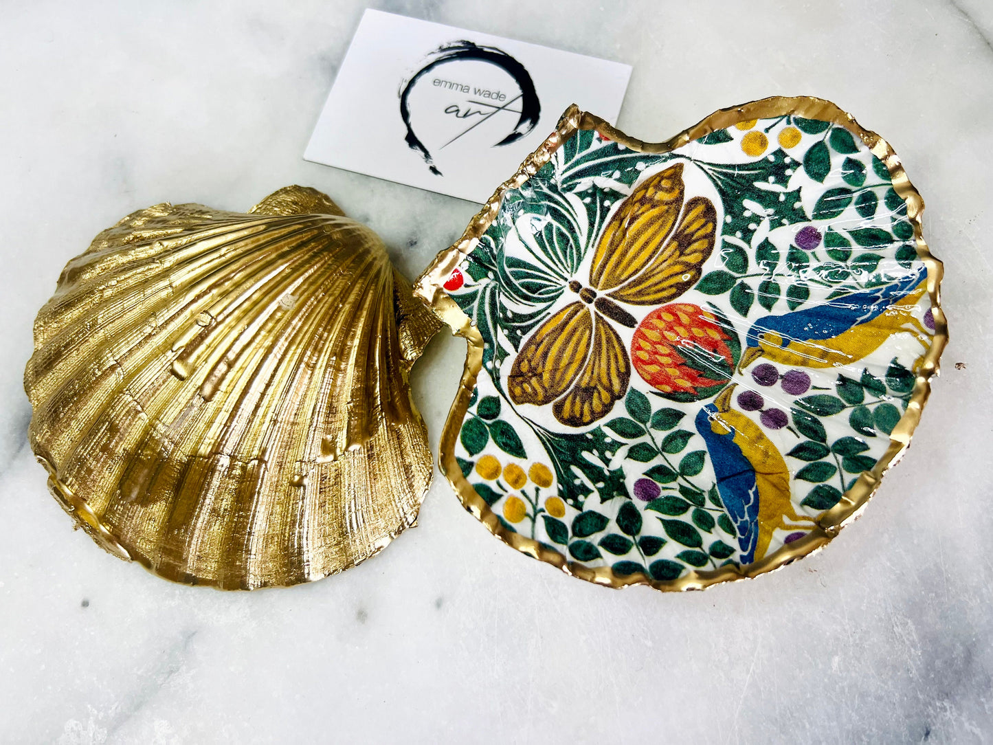 Handmade scallop shell trinket dishes with bird and butterfly design, finished with gold leaf and glossy resin, shown as decorative jewellery trays on a light background, coastal inspired handmade Dorset shell decor.