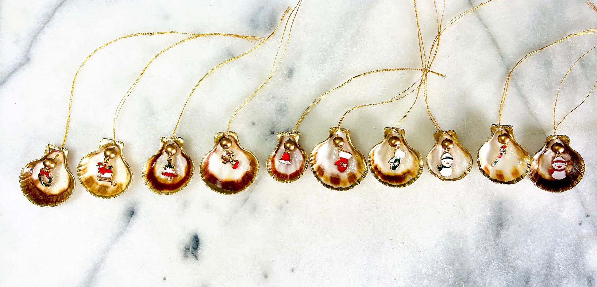 Handmade scallop shell Christmas ornaments with gold leaf edging and enamel charms, natural pearl shell decorations, Dorset shell baubles, festive tree decorations, stocking filler gifts, coastal Christmas decor, small hanging ornaments with gold string, unique handmade shell keepsake, wreath sleigh tree reindeer bell penguin charms, luxury Christmas gift idea