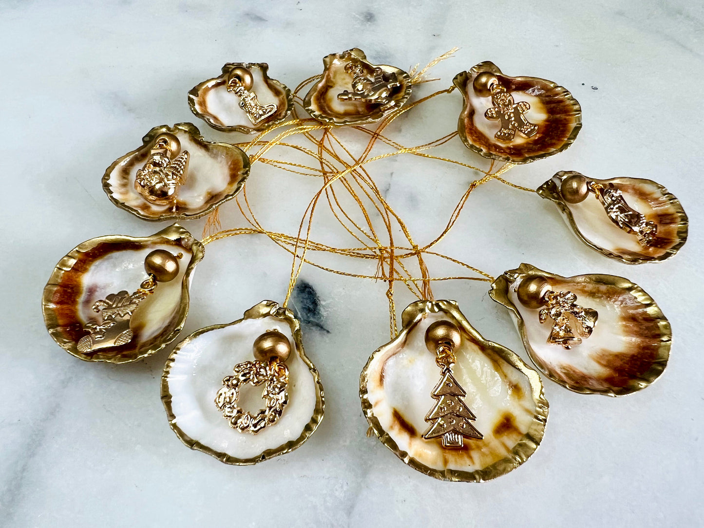 Handmade scallop shell Christmas ornaments with gold leaf edging and enamel charms, natural pearl shell decorations, Dorset shell baubles, festive tree decorations, stocking filler gifts, coastal Christmas decor, small hanging ornaments with gold string, unique handmade shell keepsake, wreath sleigh tree reindeer bell penguin charms, luxury Christmas gift idea