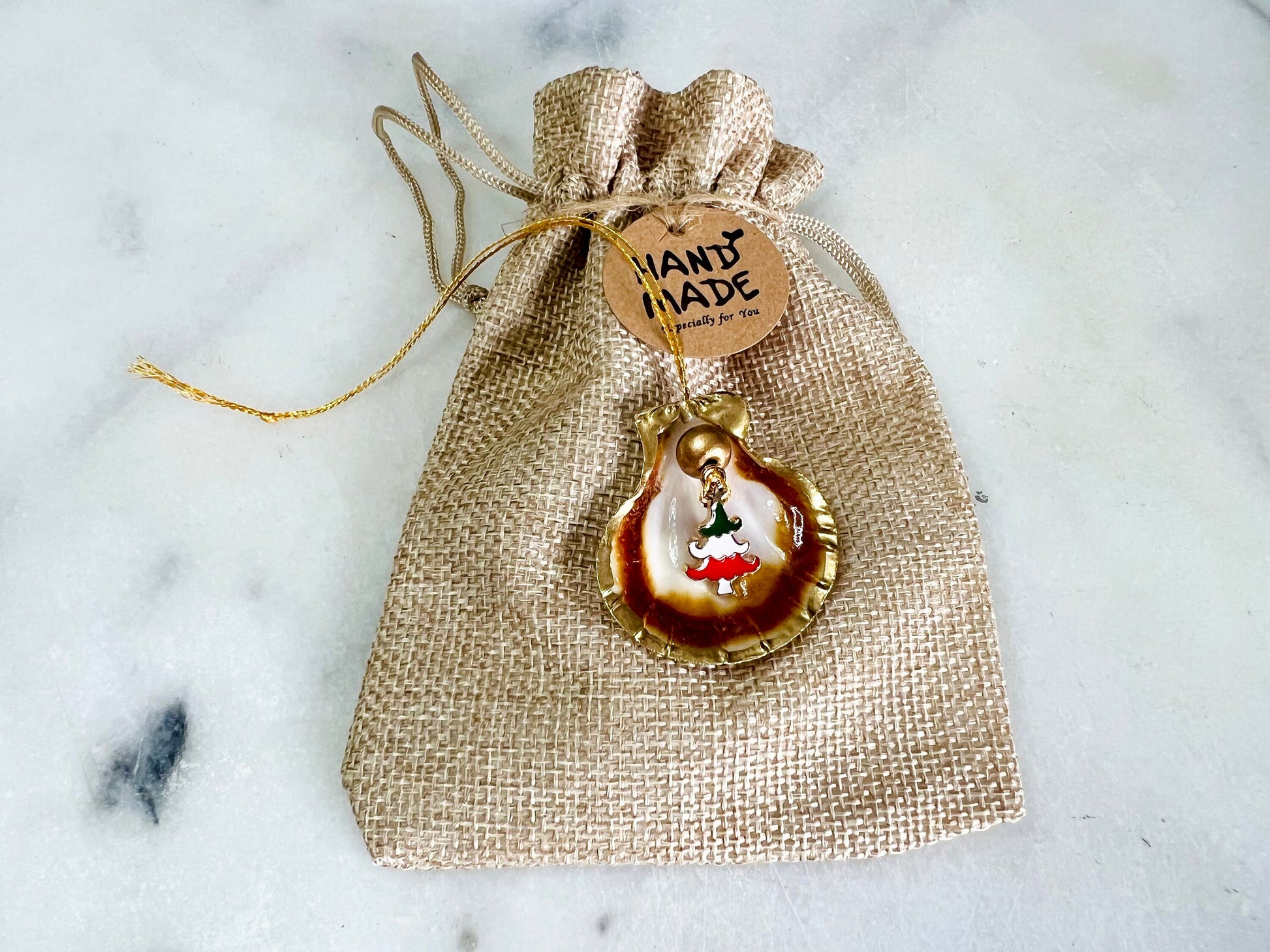 Handmade scallop shell Christmas ornaments with gold leaf edging and enamel charms, natural pearl shell decorations, Dorset shell baubles, festive tree decorations, stocking filler gifts, coastal Christmas decor, small hanging ornaments with gold string, unique handmade shell keepsake, wreath sleigh tree reindeer bell penguin charms, luxury Christmas gift idea