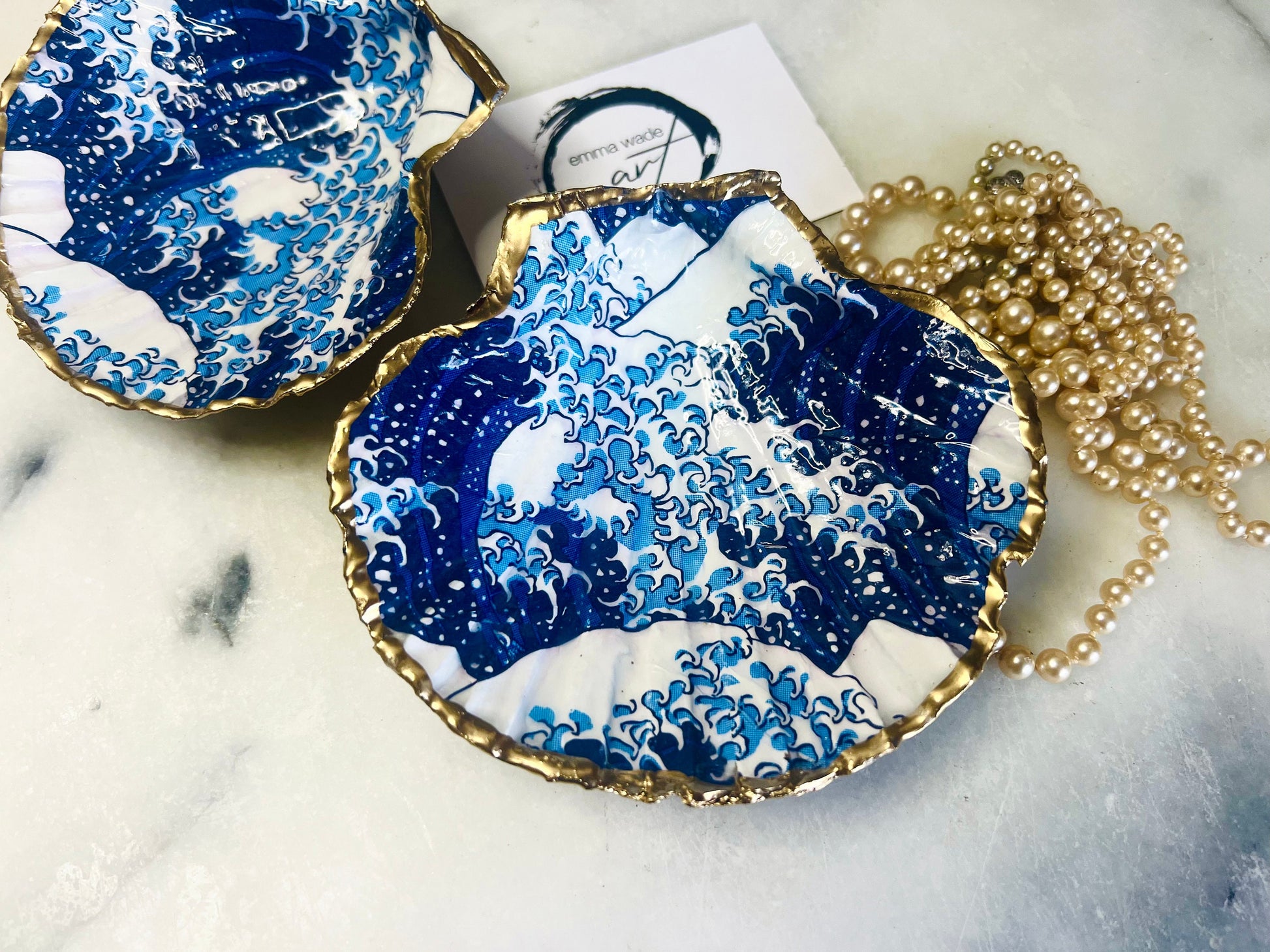 Great Wave of Kanagawa inspired scallop shell trinket dish with deep blue ocean wave artwork, gold leaf edging and glossy resin finish. Handmade coastal jewellery tray and Japanese ocean-inspired ring dish created from a natural Dorset scallop shell.