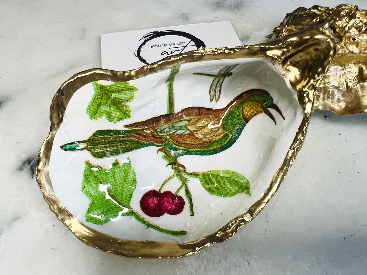 Handmade Dorset oyster shell trinket dish featuring Birds of Paradise illustration with green and brown bird designs, hand gilded with liquid gold leaf on the rim and reverse, sealed with glossy crystal clear resin, coastal jewellery holder, botanical bird decor, nature inspired oyster shell gift UK