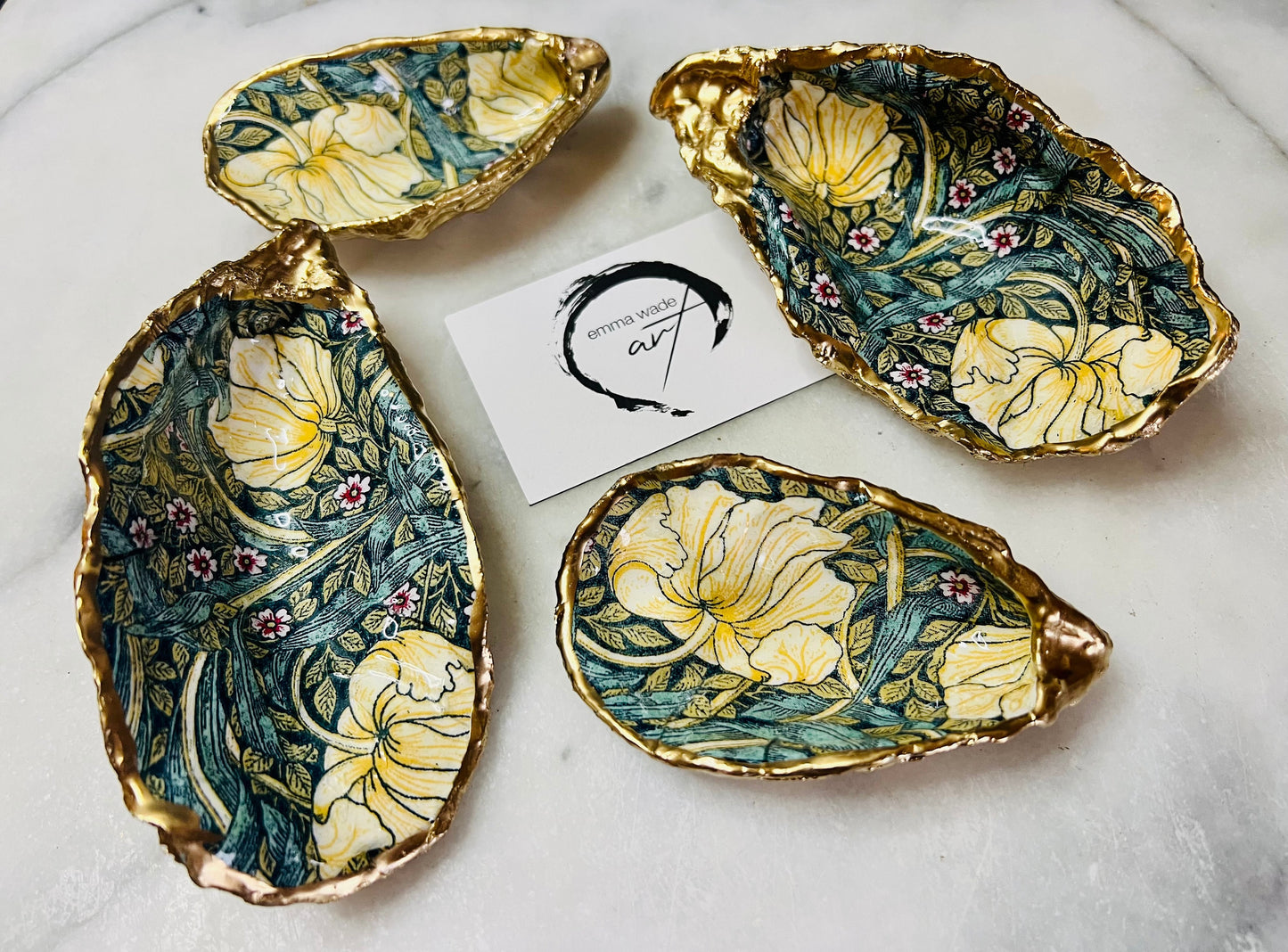 William Morris Golden Green Pimpernel oyster shell ring dish with gold leaf edge. A unique shell ring holder, ring tray, and jewellery organiser for rings, earrings, or cufflinks. Each shell features an art inspired floral design and is individually handmade from Dorset shells. Perfect as a trinket dish for bedside or dressing table storage. A thoughtful gift for weddings, anniversaries, birthdays, bridesmaids, or Christmas. A sustainable decorative keepsake for any jewellery lover.