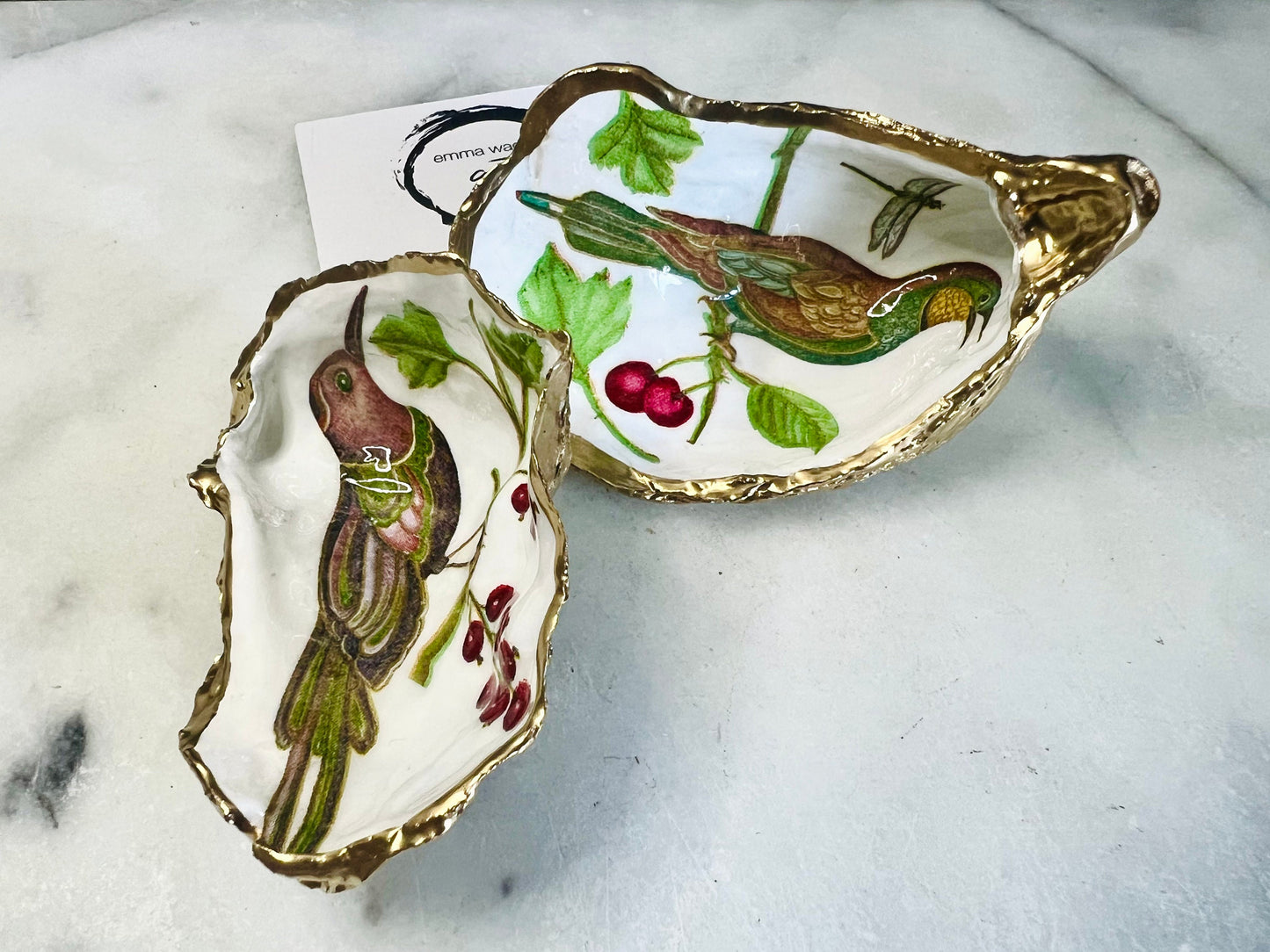 Handmade Dorset oyster shell trinket dish featuring Birds of Paradise illustration with green and brown bird designs, hand gilded with liquid gold leaf on the rim and reverse, sealed with glossy crystal clear resin, coastal jewellery holder, botanical bird decor, nature inspired oyster shell gift UK