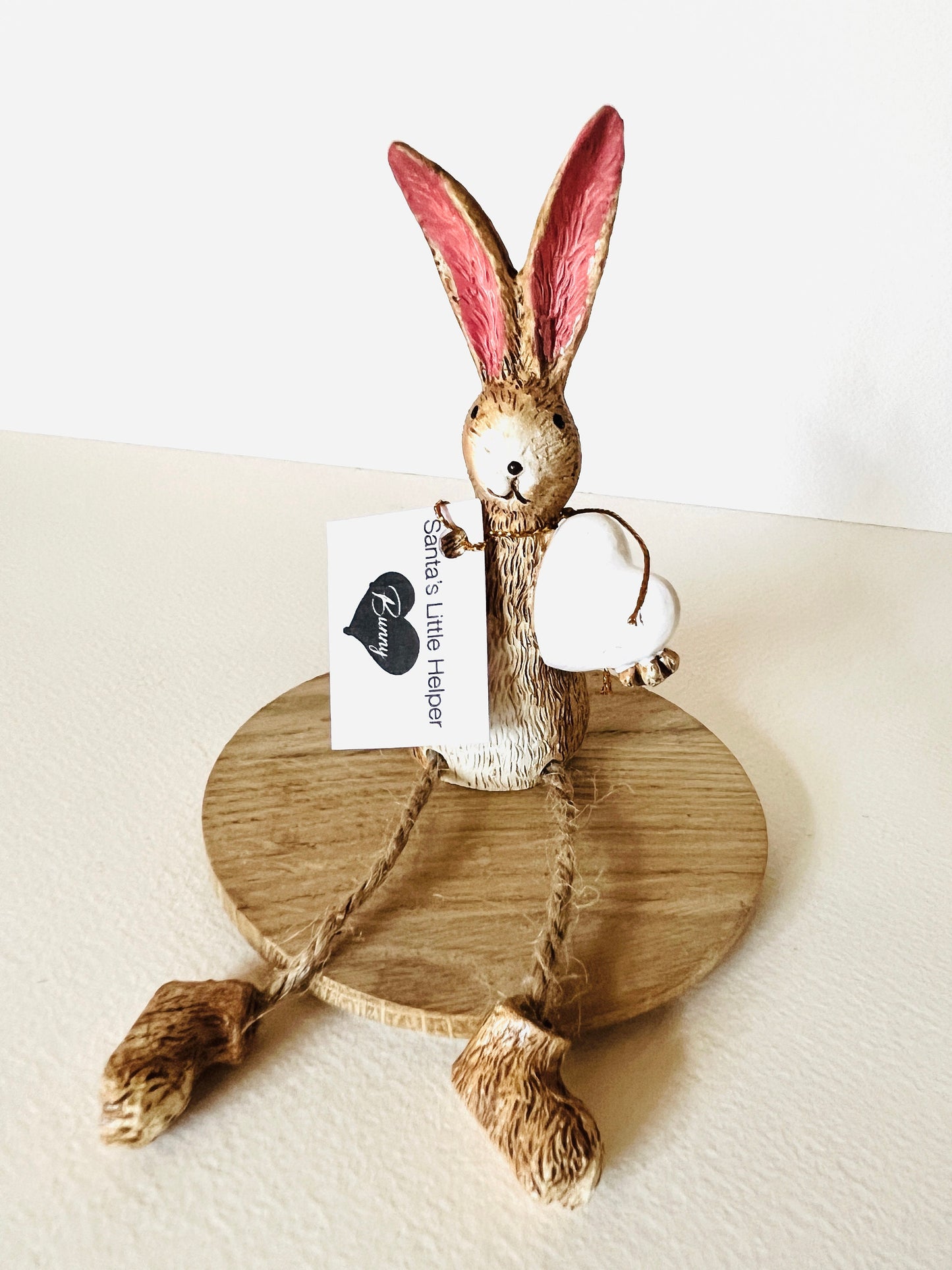 Rustic brown bunny shelf sitter with white heart and dangling jute legs, hand finished polyresin rabbit ornament for spring and cottage style home decor. Perfect Mother’s Day gift or a gift for her.