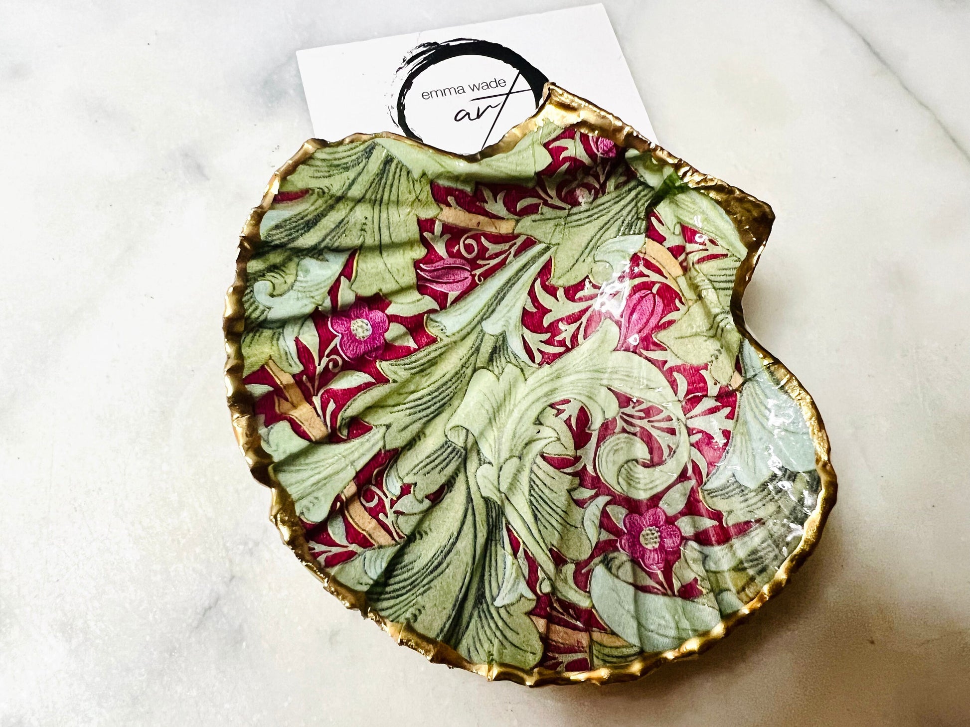 Handmade Dorset scallop shell trinket dish featuring William Morris Granville Bordeaux pattern, finished with real gold leaf edging and a glossy resin coating. A sustainable coastal jewellery dish and ring holder, individually handcrafted in the UK. Ideal as a unique gift for her, wedding or anniversary present, or elegant home décor accent inspired by nature and classic Arts and Crafts design.