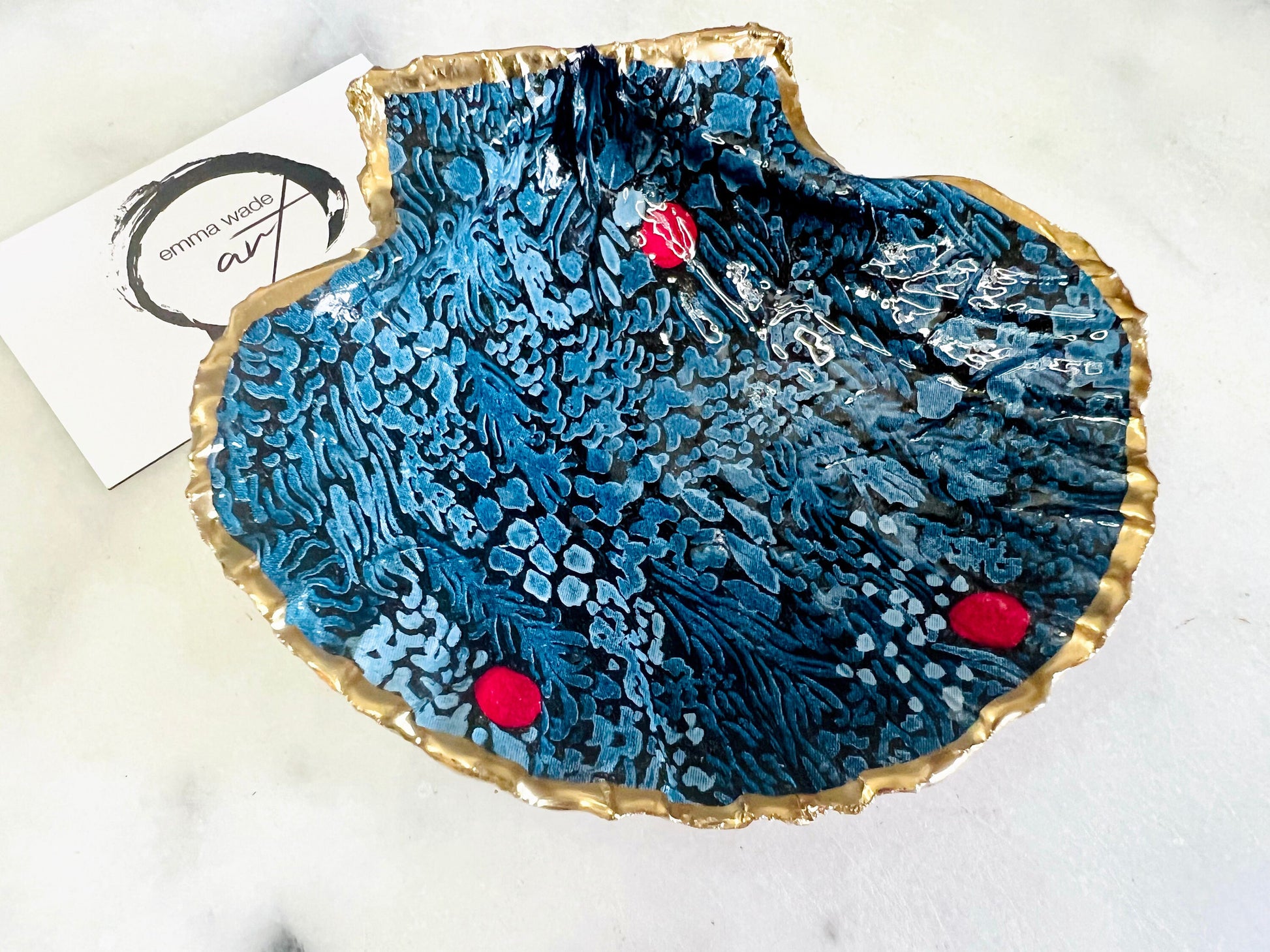Handmade Marimekko inspired scallop shell trinket dish featuring bold Scandinavian floral design in deep blue with red accents. Natural Dorset scallop shell hand gilded with liquid gold leaf edging and sealed with glossy resin for a luxurious shine. Coastal home décor suitable as a jewellery dish, ring tray, trinket holder, wedding gift, bathroom décor or modern Nordic inspired shelf styling. Unique handcrafted shell décor inspired by botanical Scandinavian design.