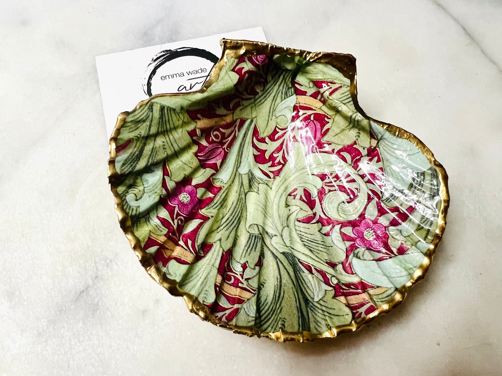 Handmade Dorset scallop shell trinket dish featuring William Morris Granville Bordeaux pattern, finished with real gold leaf edging and a glossy resin coating. A sustainable coastal jewellery dish and ring holder, individually handcrafted in the UK. Ideal as a unique gift for her, wedding or anniversary present, or elegant home décor accent inspired by nature and classic Arts and Crafts design.