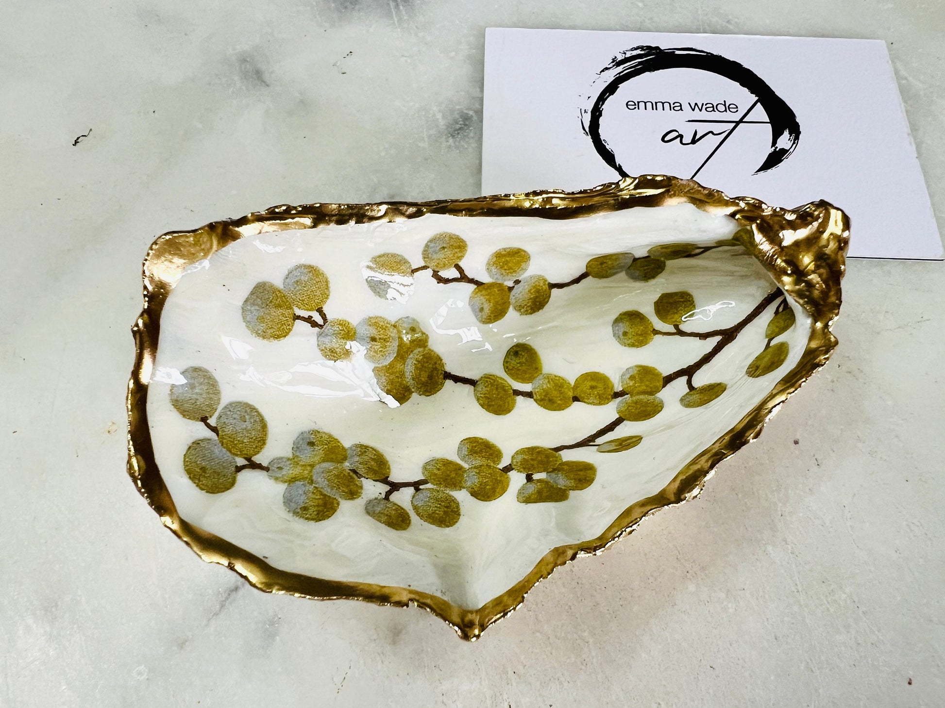 Handmade Dorset oyster shell dish with a gold and white berries design, gilded with liquid gold leaf on the rim and back, and sealed in crystal-clear resin for a glossy shine. Each oyster shell jewellery dish is unique, perfect as a ring holder, trinket tray, or organiser for earrings, cufflinks, and small keepsakes. A meaningful handmade oyster ring dish for weddings, anniversaries, birthdays, bridesmaids, or festive celebrations. Ideal as UK coastal-inspired home décor.