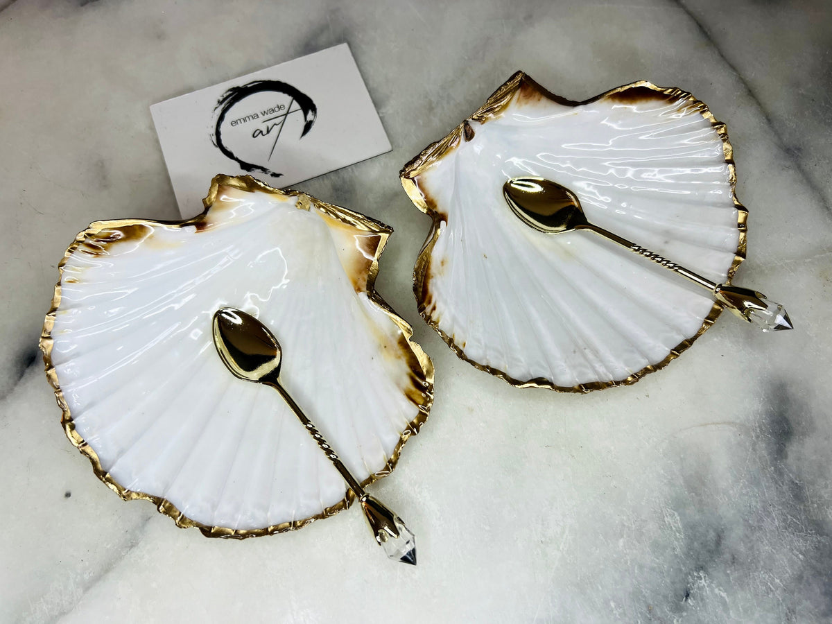 Pair of handmade Dorset scallop shell salt and pepper pinch pots with polished pearl finish, gold leaf edging, and optional gold crystal spoons or serving tongs. Elegant coastal shell cruet set styled for luxury dining and wedding table décor.